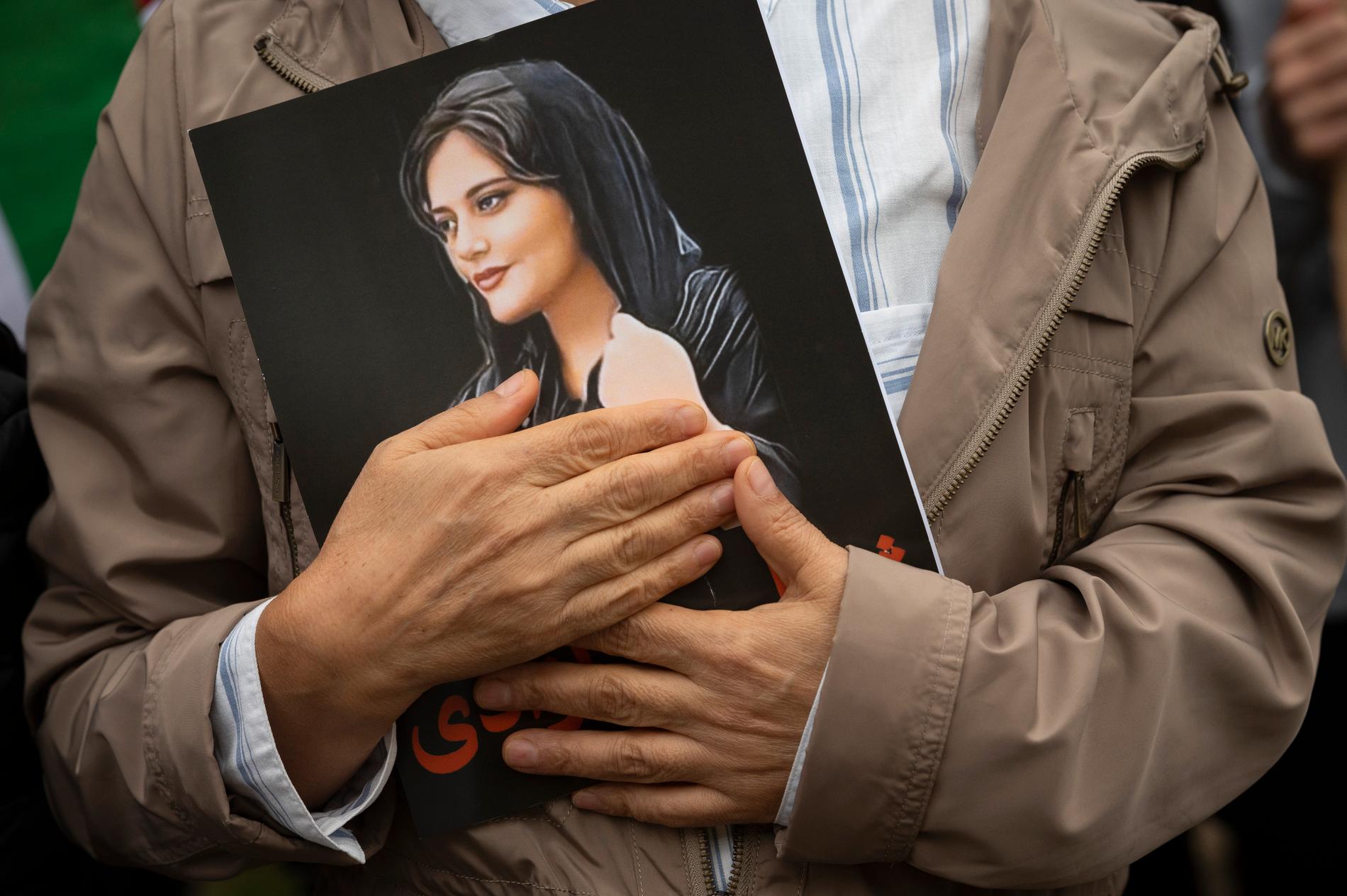 Washington, USA. Under en protestsamling den 1 oktober håller en deltagare försiktigt i ett portträtt av Mahsa Amini, som bara blev 22 år. 
