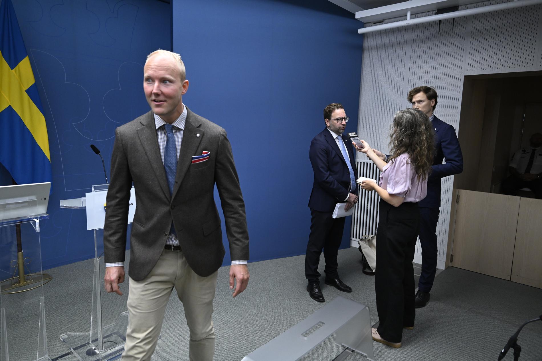 SD:s Ludvig Aspling går iväg medan Liberalernas Fredrik Malm intervjuas efter pressträffen. 