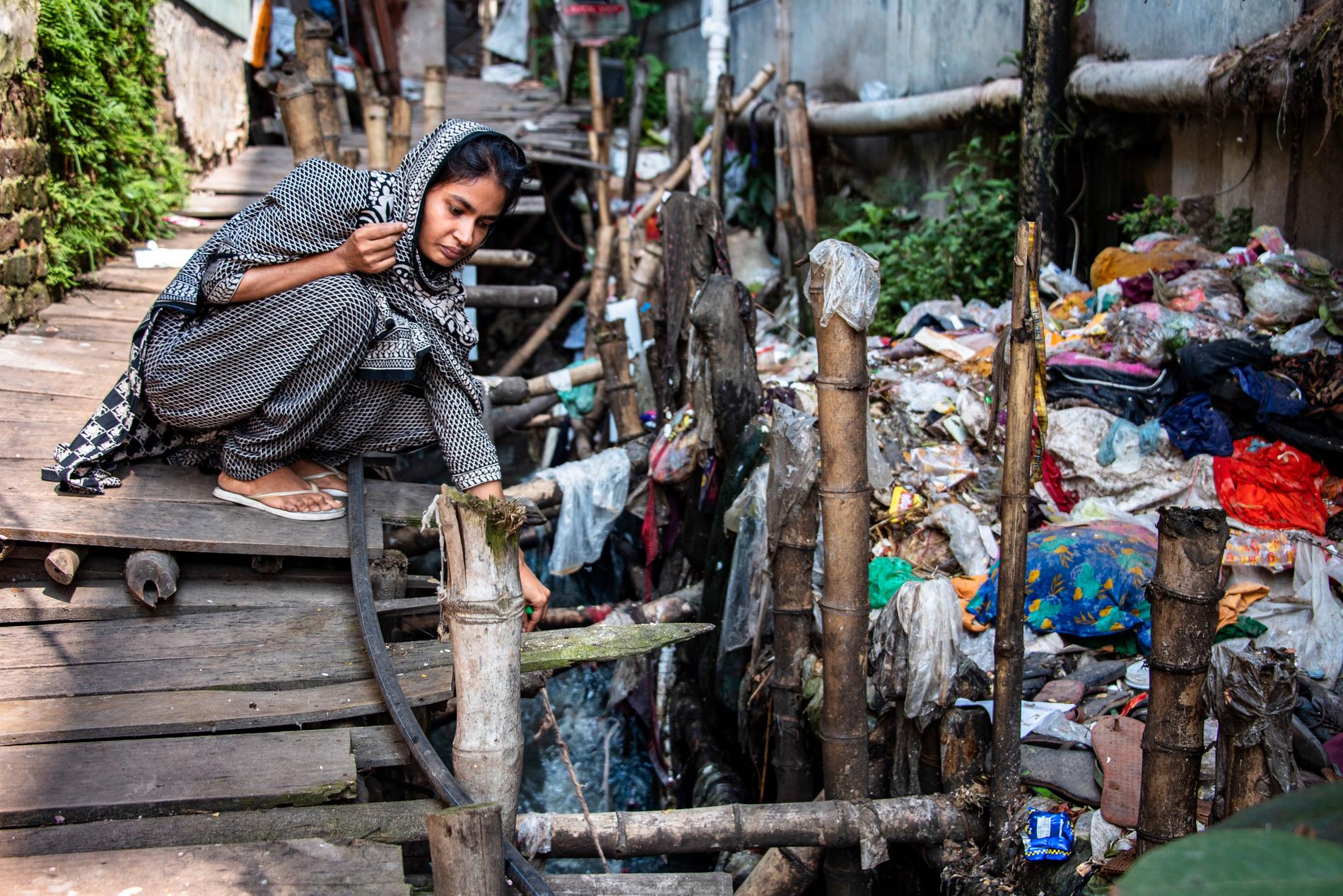Klädfabriker släpper ut förorenat vatten. Soma Akhter, 25, bor i huset ovanpå utsläppsån.