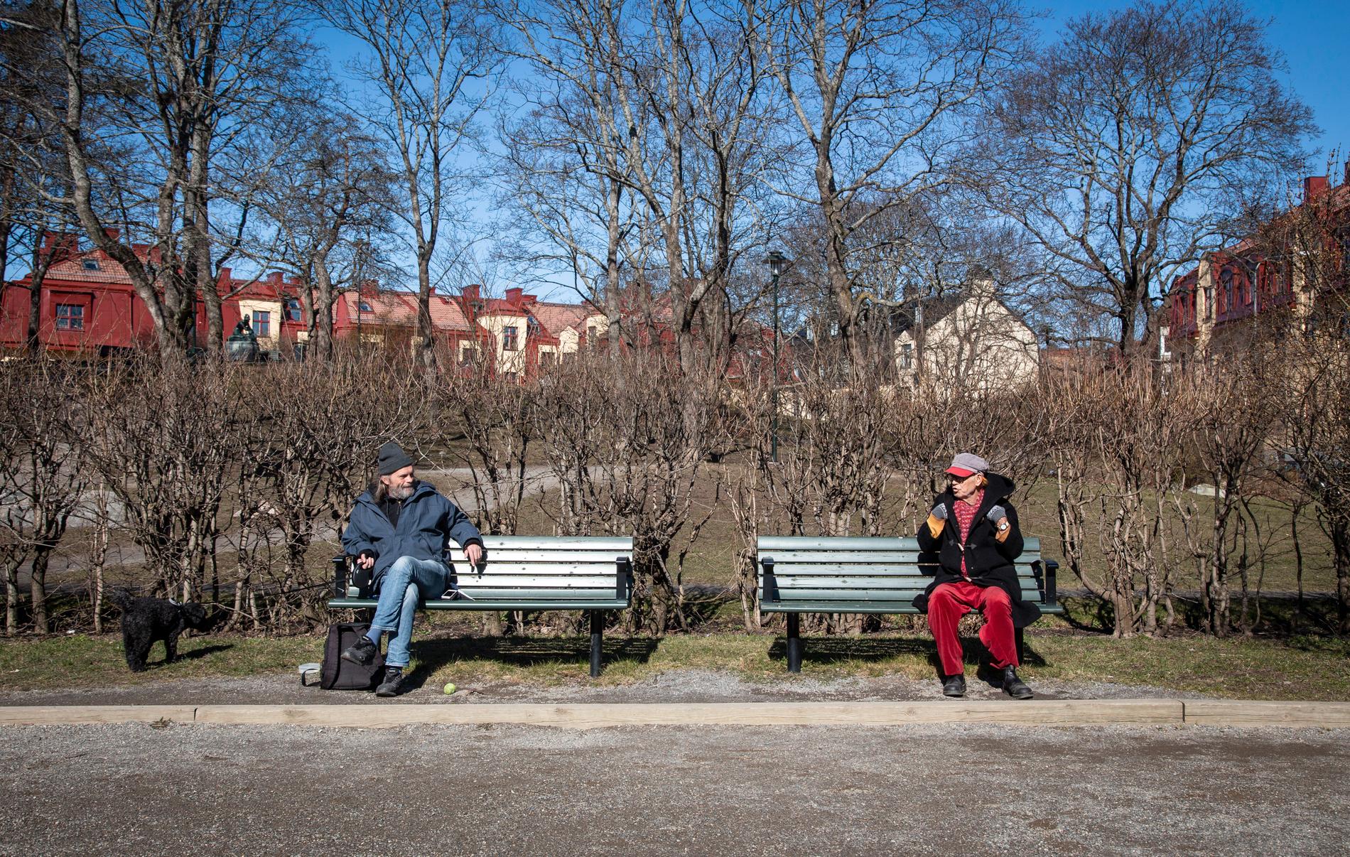 Två män som håller social distans – men ändå passar på att njuta av våren i Stockholm.