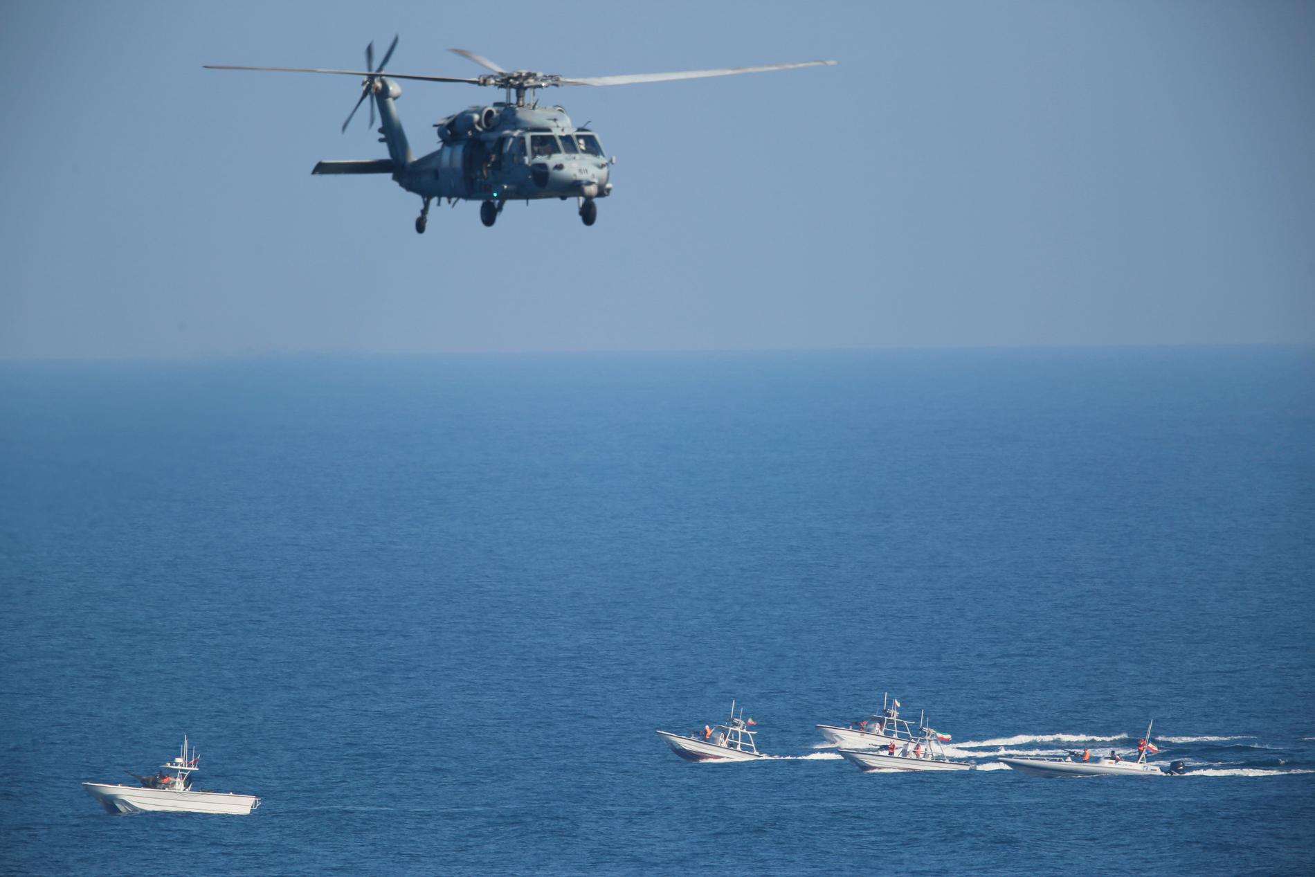 En amerikansk helikopter flyger ovanför båtar från det iranska revolutionsgardet i december 2018, då det amerikanska hangarfartyget USS John C. Stennis seglade in i Persiska viken. Arkivbild.