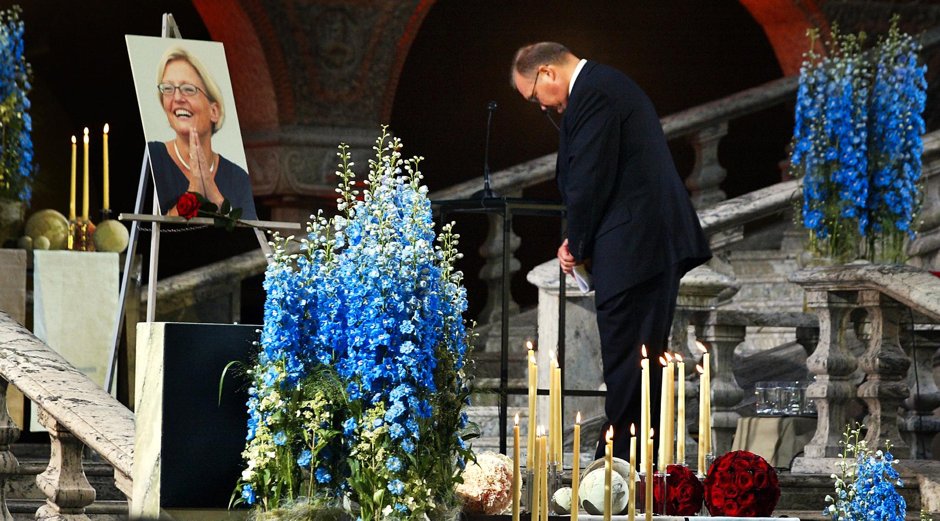 Göran Persson bugar framför Anna Lindhs porträtt på begravningen 2003.