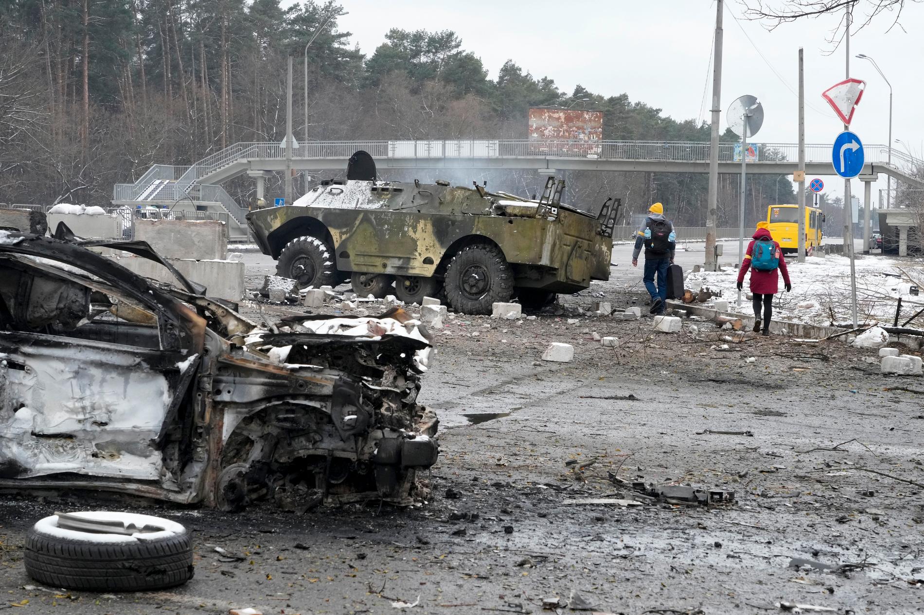 Människor går förbi ett utbränt militärfordon vid Brovary utanför huvudstaden Kiev. 