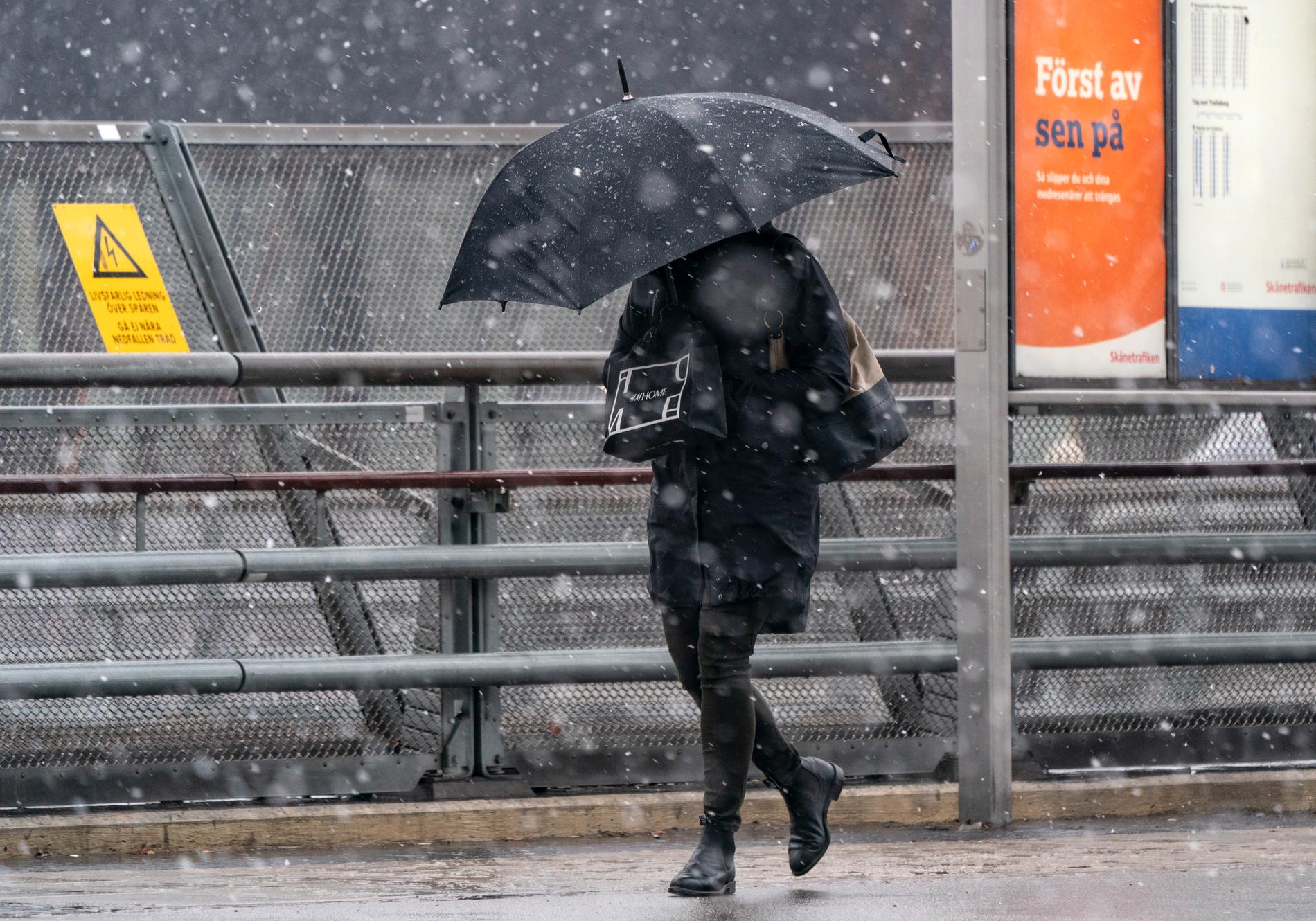 Paraply som skydd mot snöblandat regn och hårda vindar vid Hyllie C i Malmö när stormen Evert drog in över södra Sverige på torsdagen.