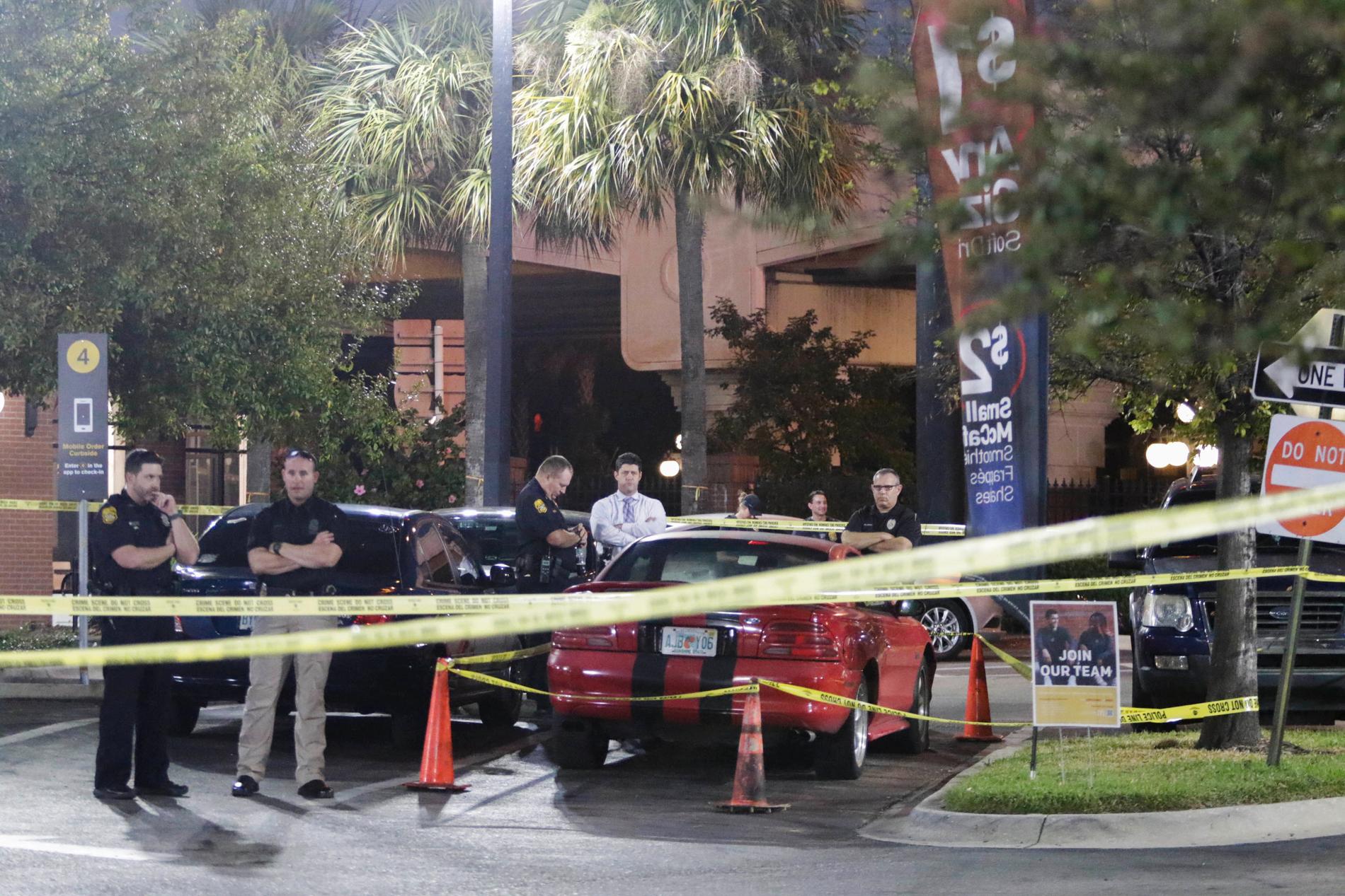 Poliser går igenom eventuella bevis och en sportbil vid McDonald’s i Ybor City, Tampa. 
