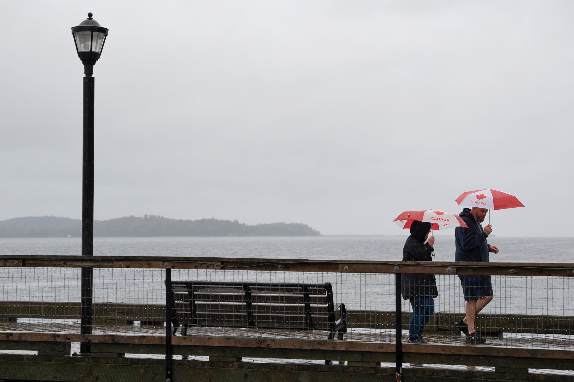 Människor på promenad i regnet, längs med en kaj i Halifax, provinshuvudstaden i kanadensiska Nova Scotia.