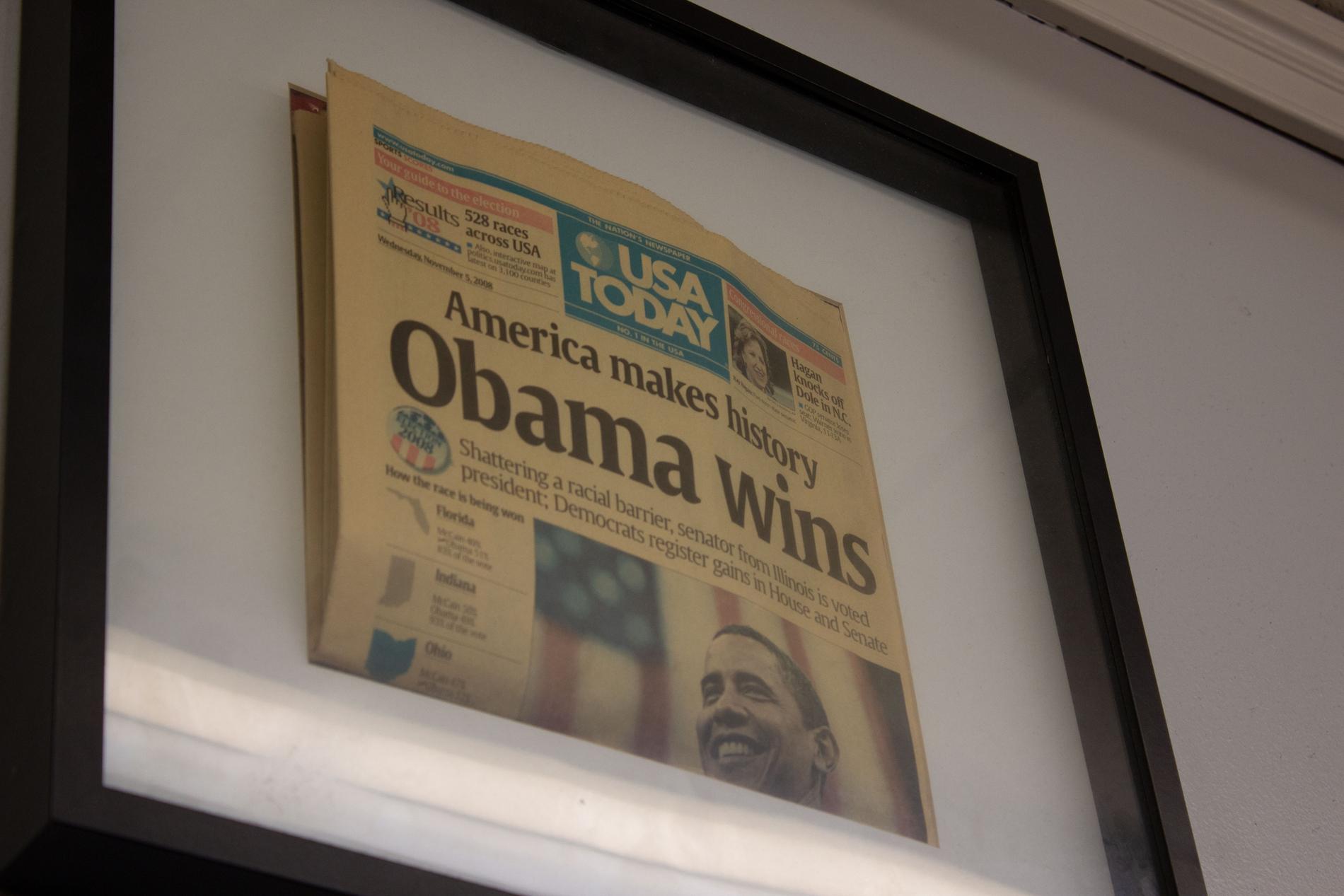 På väggen hänger förstasidan av tidningen från dagen då Obama vann presidentvalet.