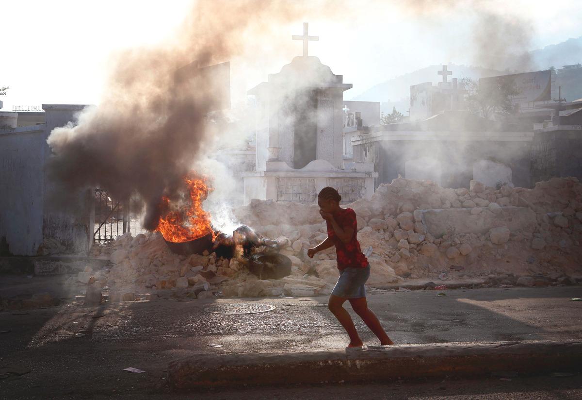 FLYR STANKEN En kropp ligger och brinner på öppen gata i Port-au-Prince. En förbipasserande flicka måste hålla för mun och näsa för att undvika den stank som den döda kroppen sprider. På andra sidan vägen fortgår gatuhandeln precis som vanligt.
