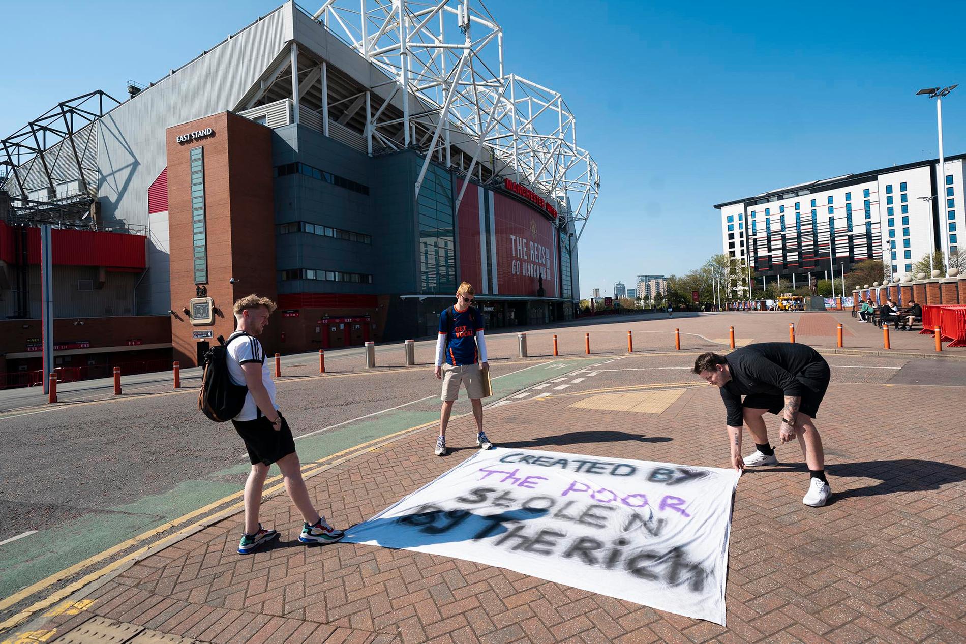 Supportrar utanför Manchester Uniteds hemmaarena Old Trafford lägger ut en banderoll som protesterar mot planerna på en superliga.