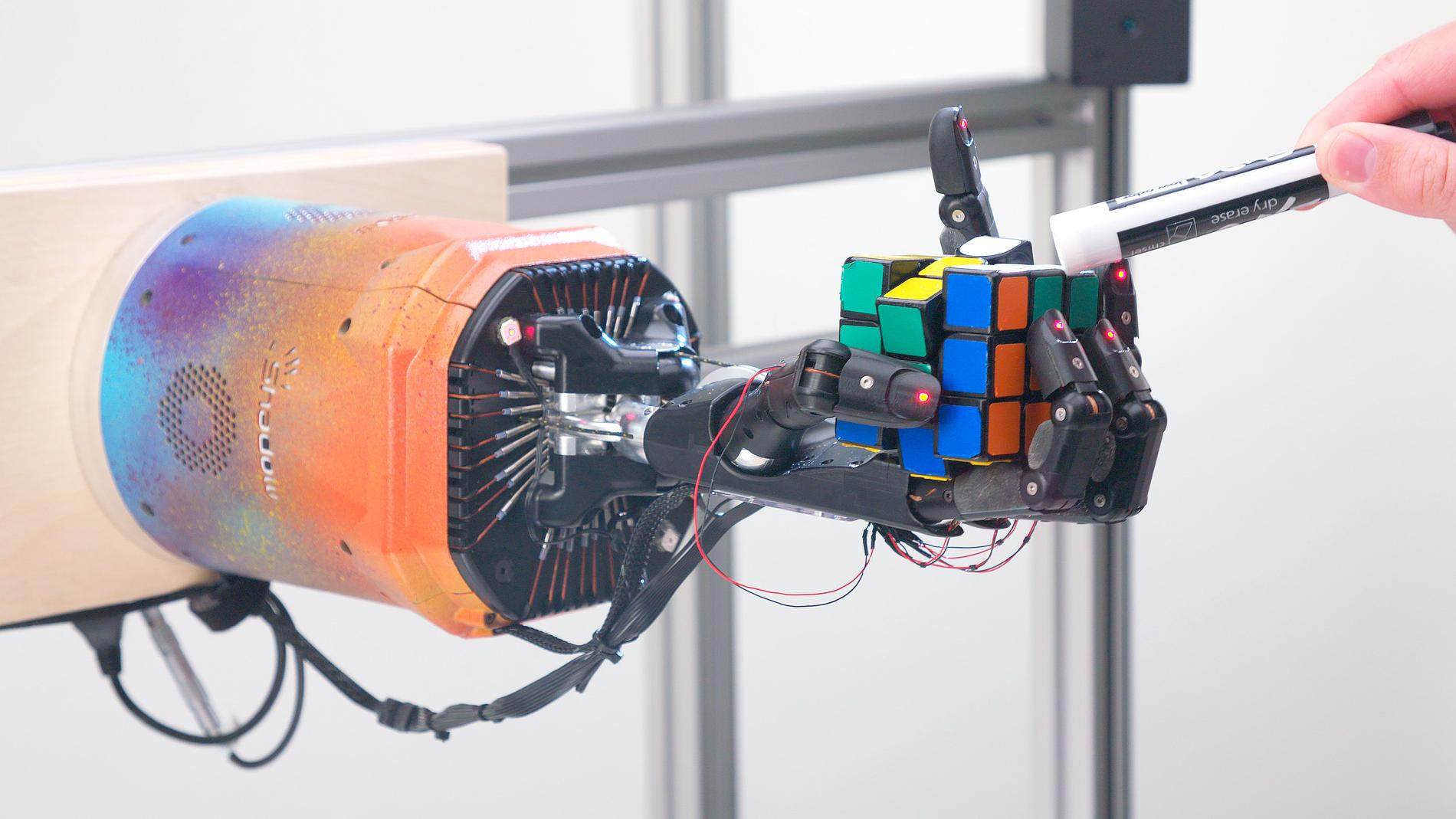 Robothanden klarar av att lösa kuben även när forskarna petar på den med en penna.