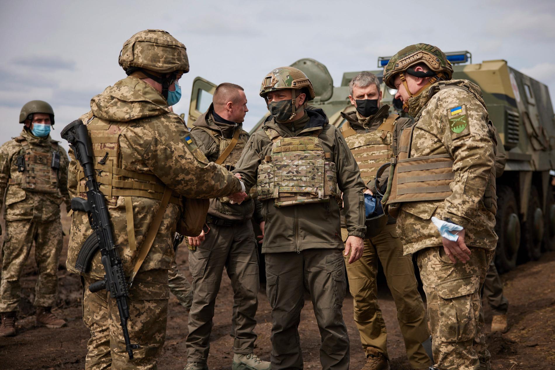 Ukrainas president Volodymyr Zelenskyj (i mitten) besöker landets soldater i östra Ukraina på torsdagen. På andra sidan gränsen mobiliserar Ryssland.