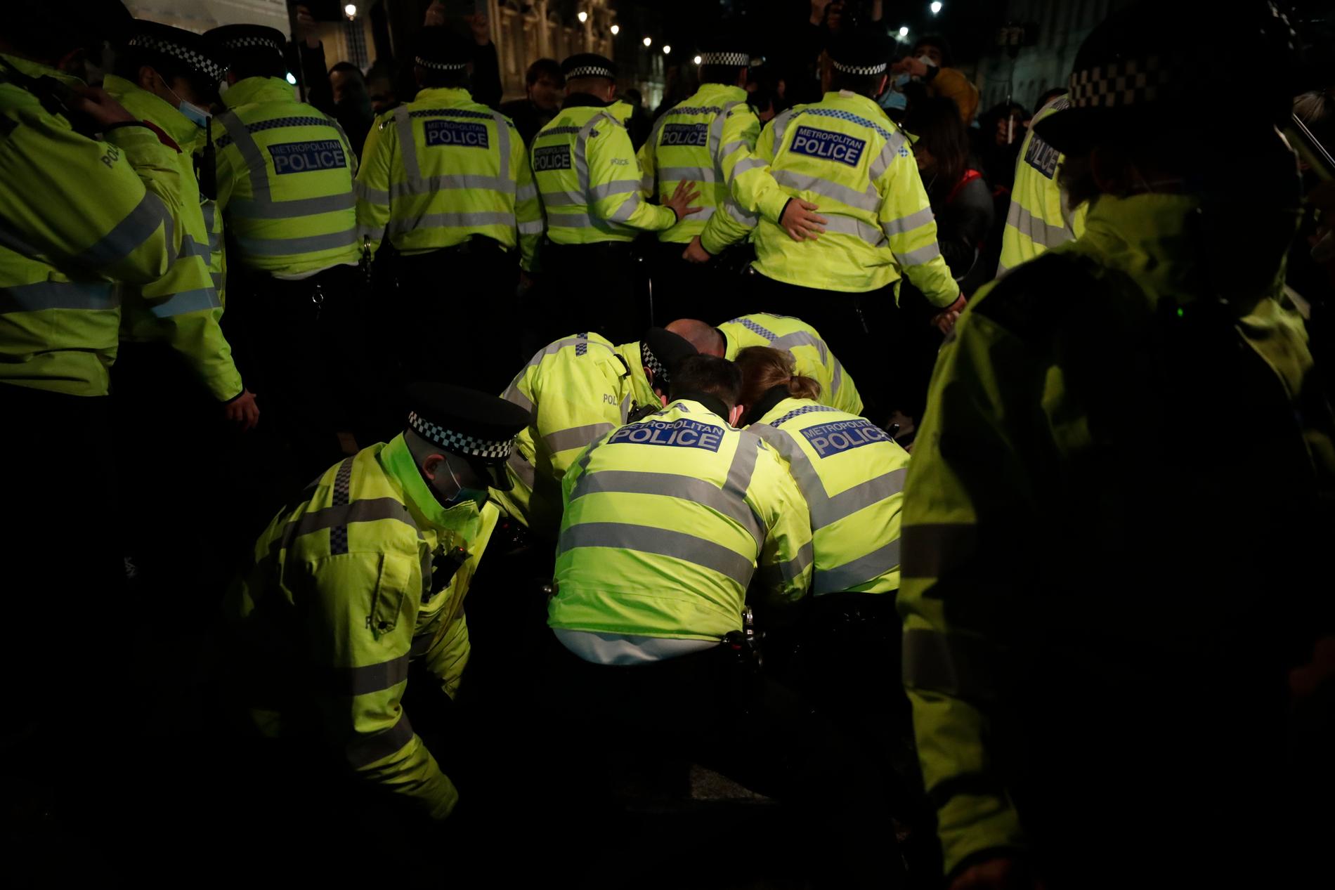 Polisen håller fast en man efter att de uppmanat demonstranter att gå hem. 