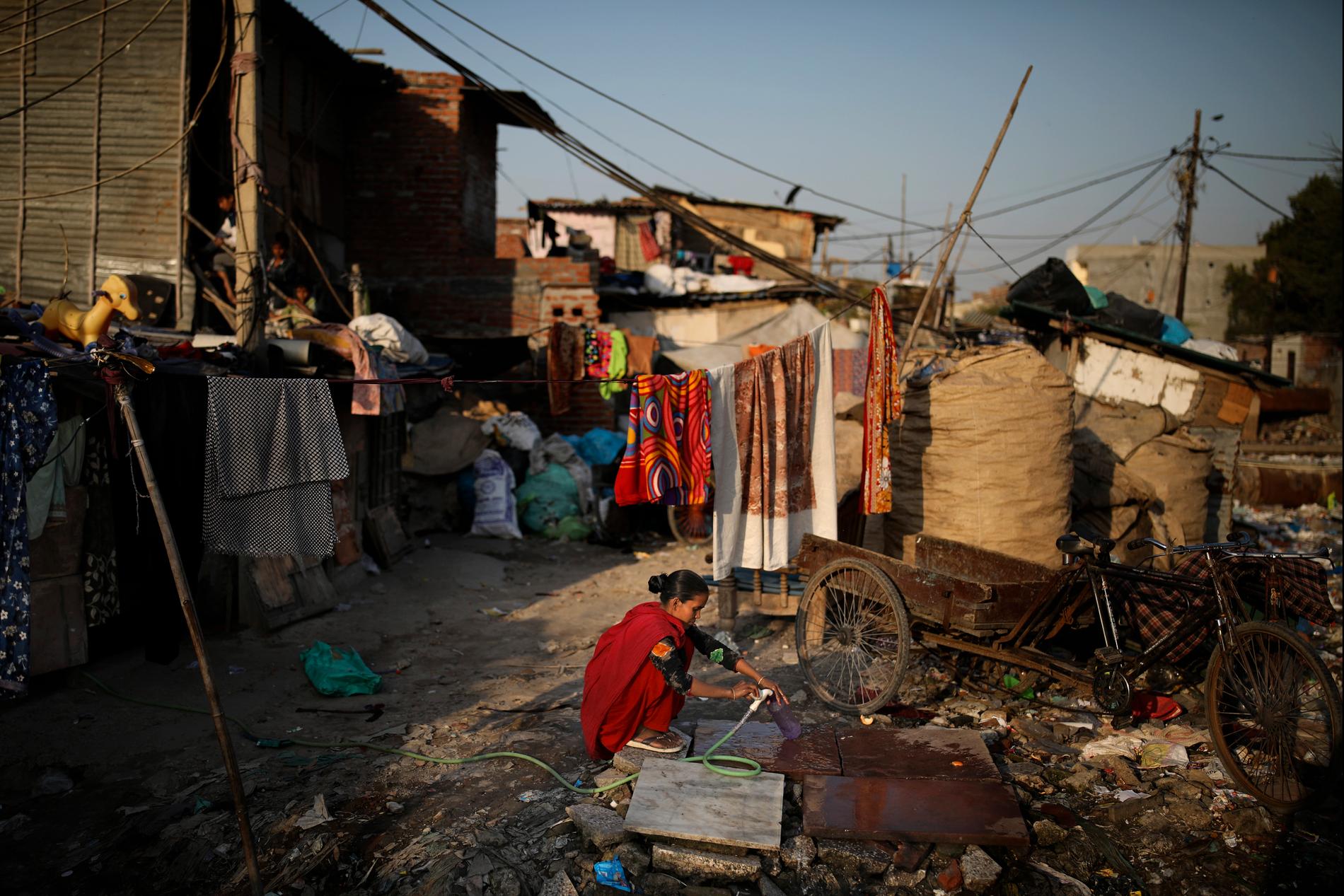 En kvinna hämtar vatten i ett av den indiska huvudstaden Delhis slumområden. Bristen på rinnande vatten i världens kåkstäder förväntas förvärra smittspridningen allvarligt.