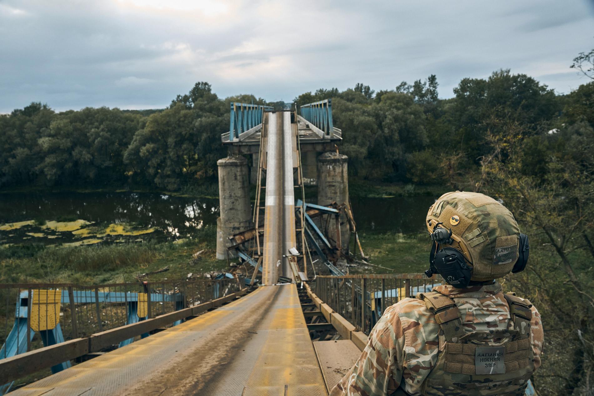 En ukrainsk soldat står på en förstörd bro i Izium i Charkiv-regionen.