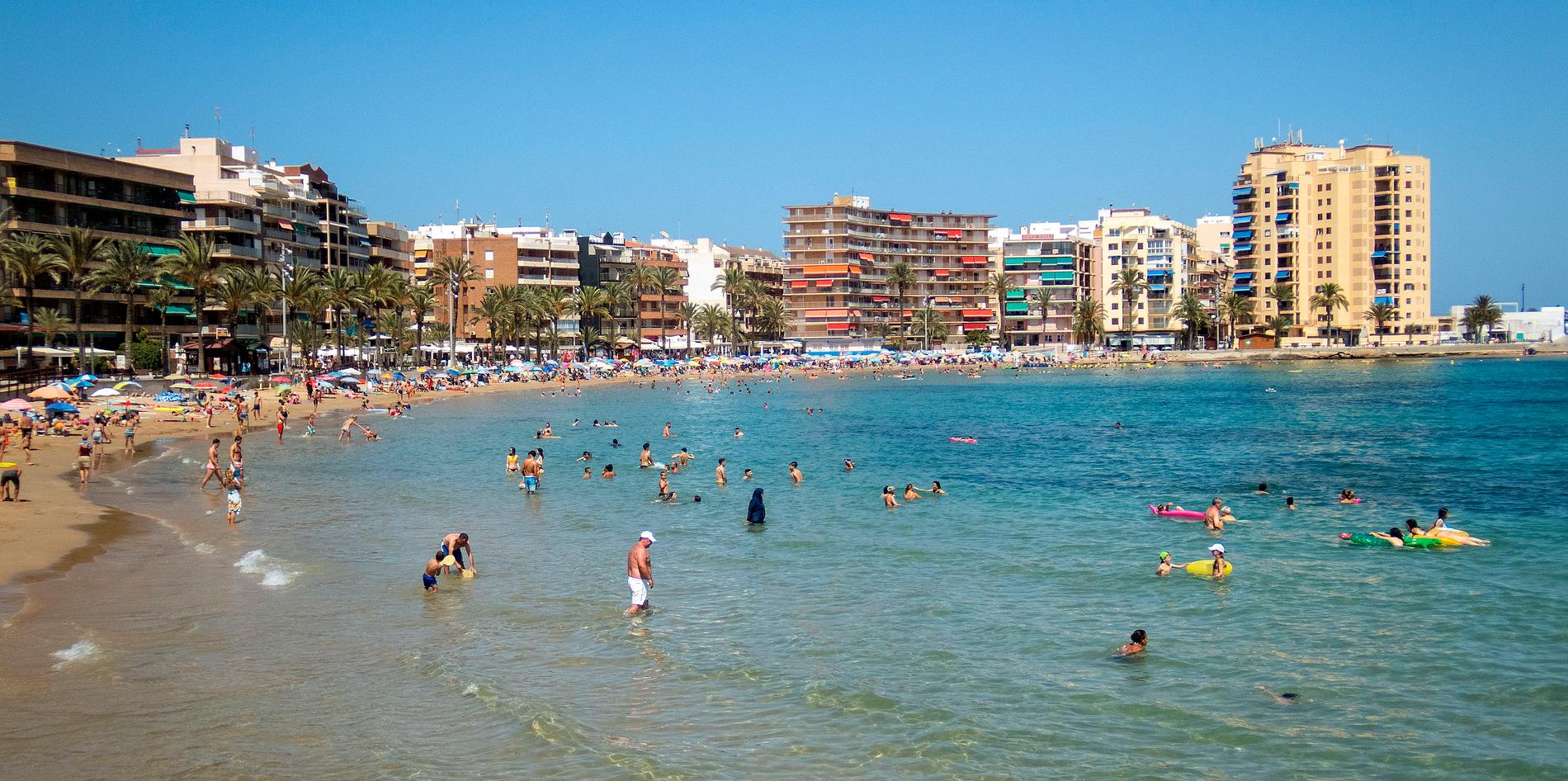 Badgäster njuter på stranden Playa del Cura i Torrevieja.  Längtar du dit? I sommar kan det vara möjligt att resa till Spanien igen. 
