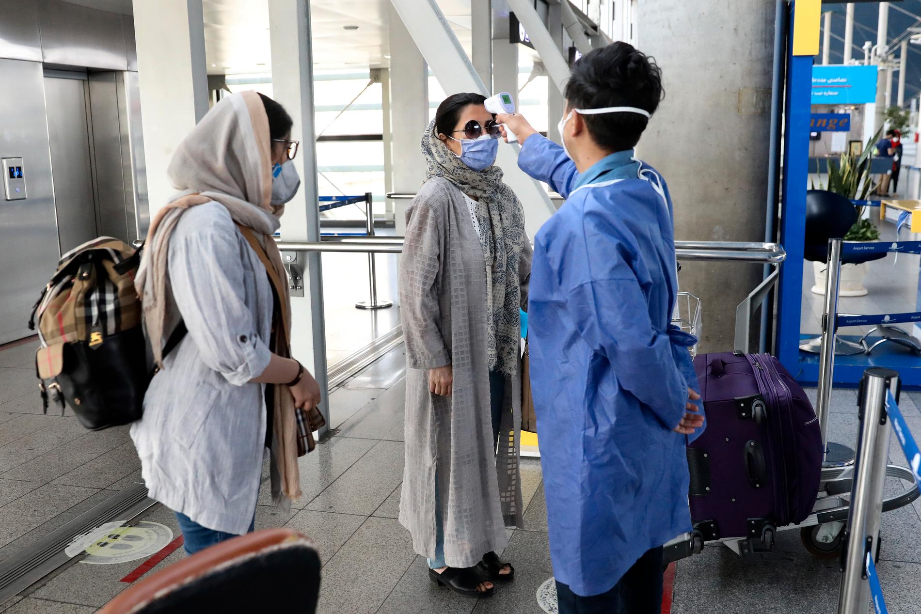 Vårdpersonal kontrollerar temperaturen på passagerare som anländer till Teheran. Arkivbild.