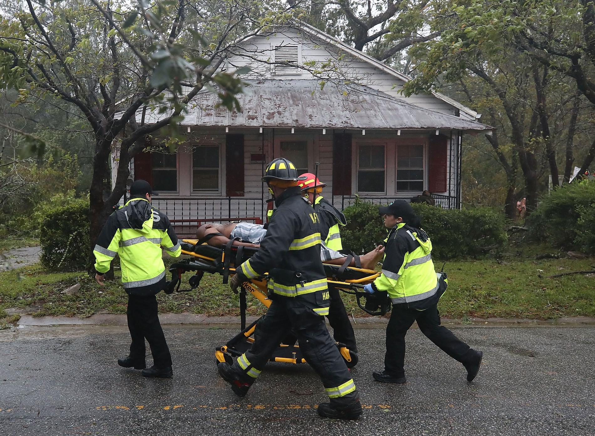 Räddningspersonal hämtar en man från ett hus som ett stort träd fallit på. 
