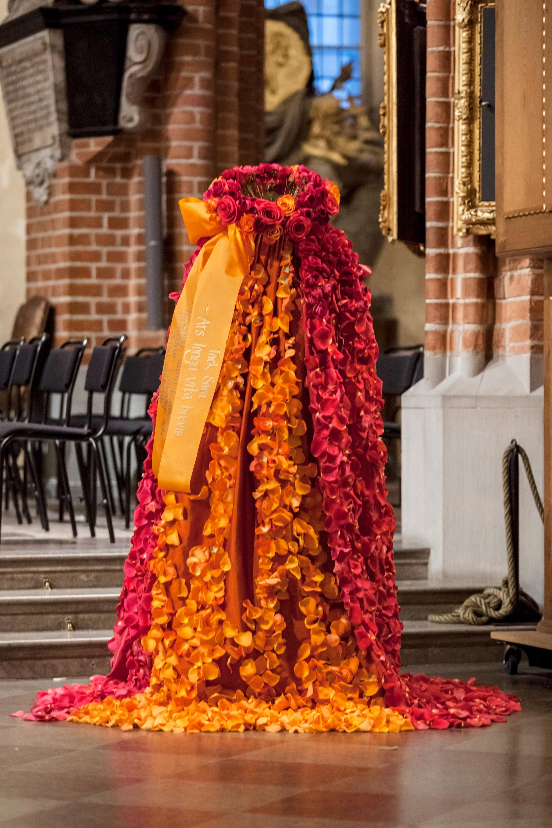 En otrolig blomsterklänning, skapad av blomblad i cerise och orange.