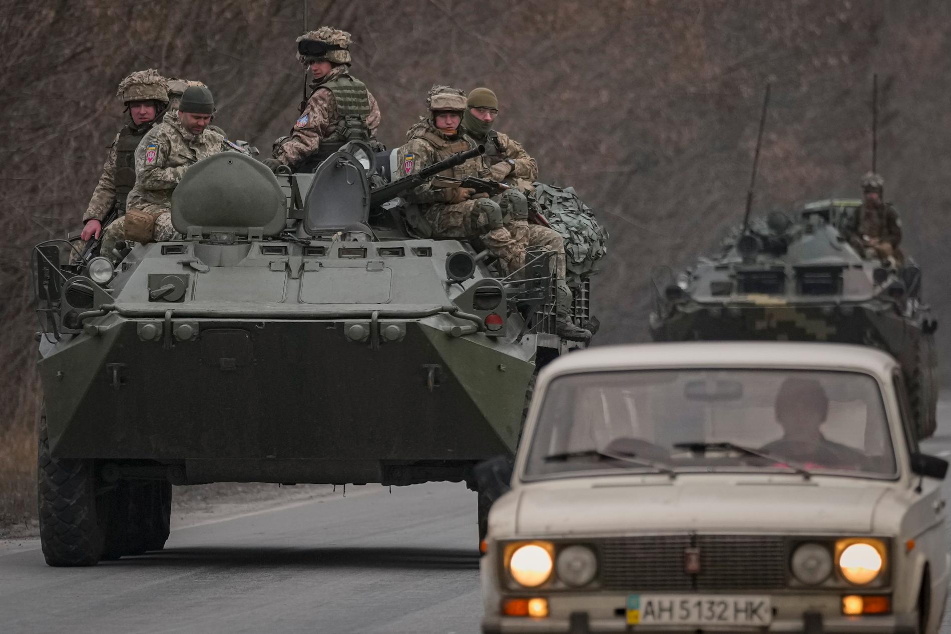Personbilar och stridsvagnar färdas på samma väg vid Donetsk i östra Ukraina.
