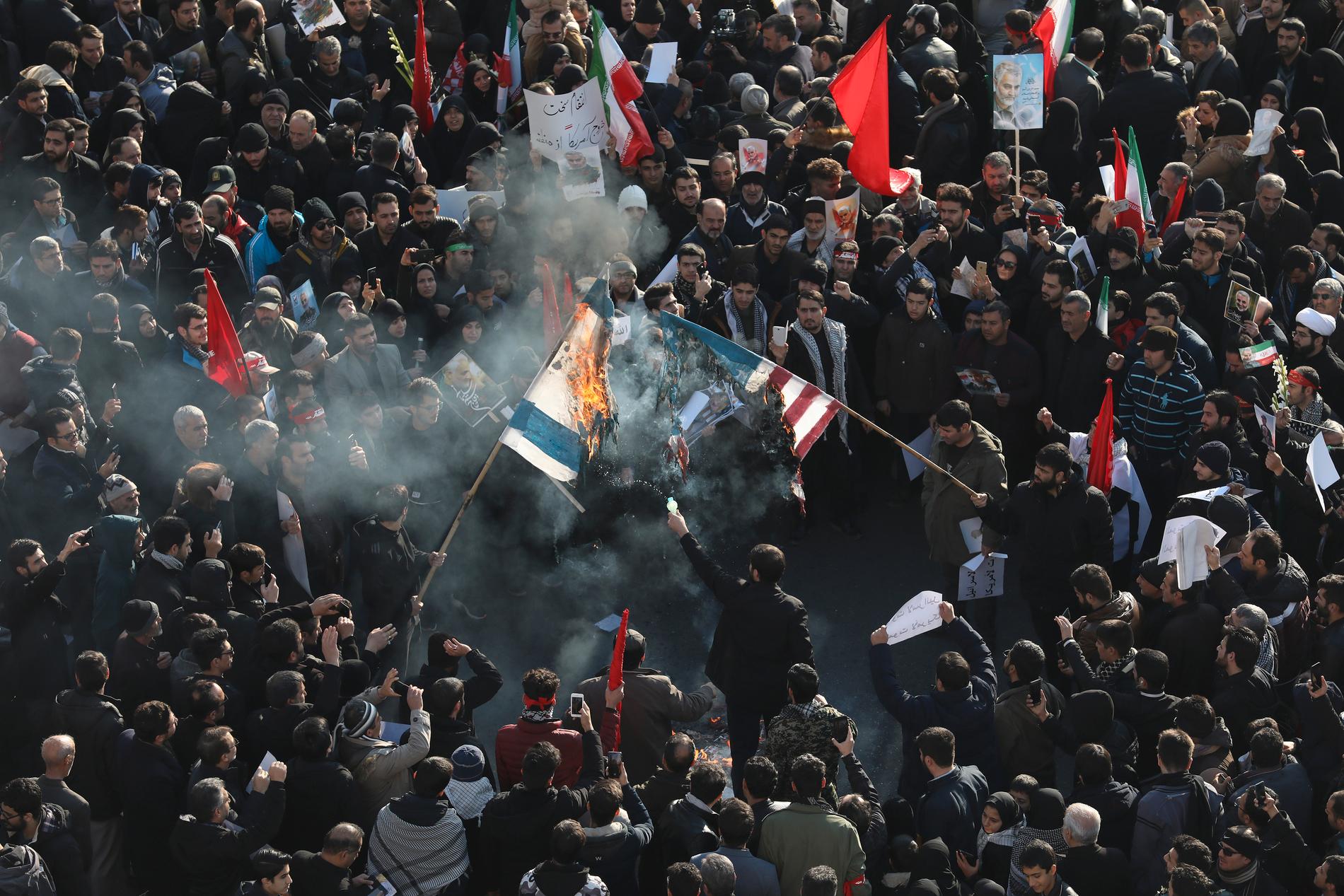 USA:s och Israels flaggor bränns under begravningsprocessen i Teheran för toppgeneralen Qassem Soleimani som i fredags dödades av en amerikansk drönare.