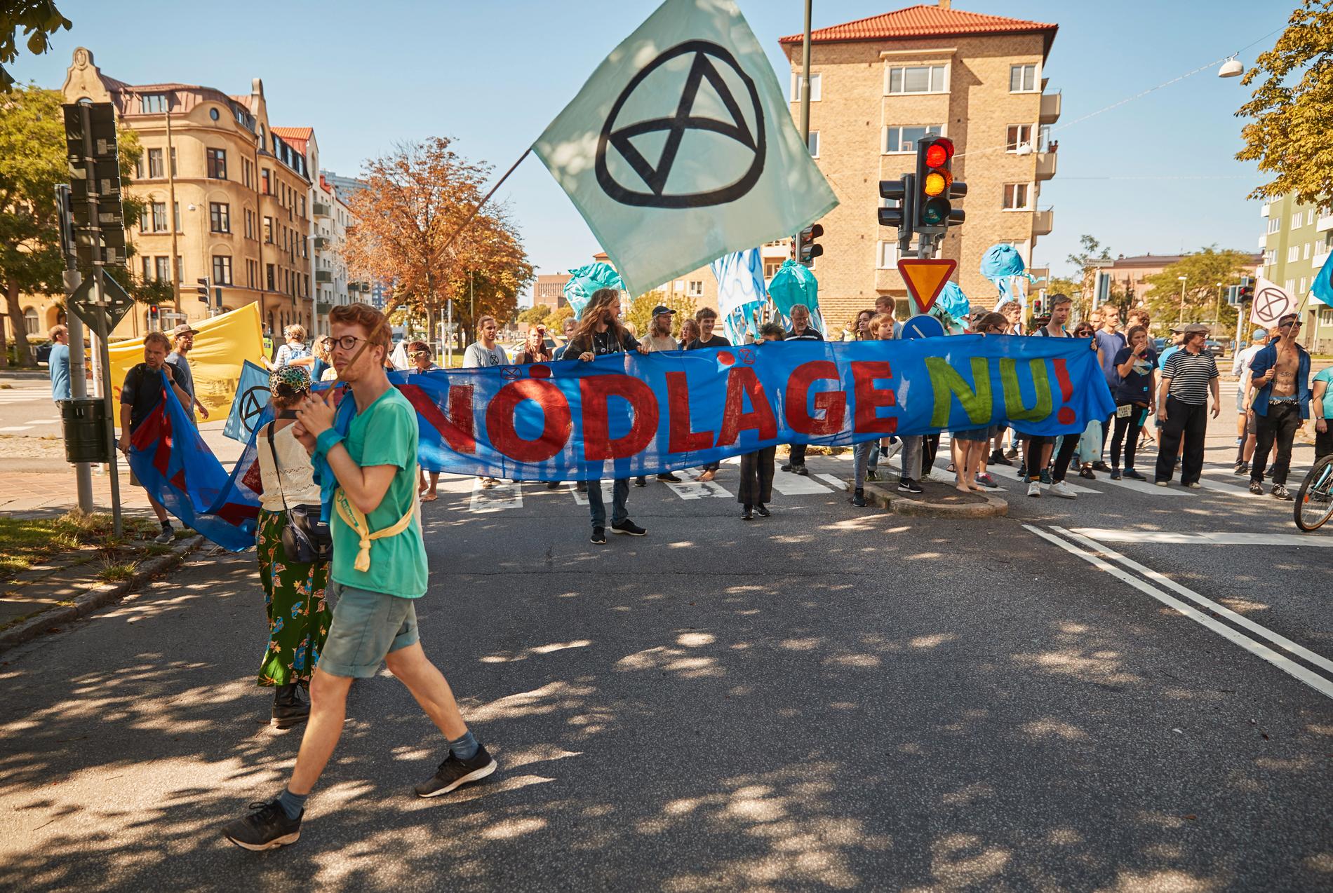 "Klimatnödläge" står det på en banderoll som demonstranter från rörelsen Extinction Rebellion håller upp när de spärrade av en korsning längs Östra Rönneholmsvägen i Malmö i augusti i år.