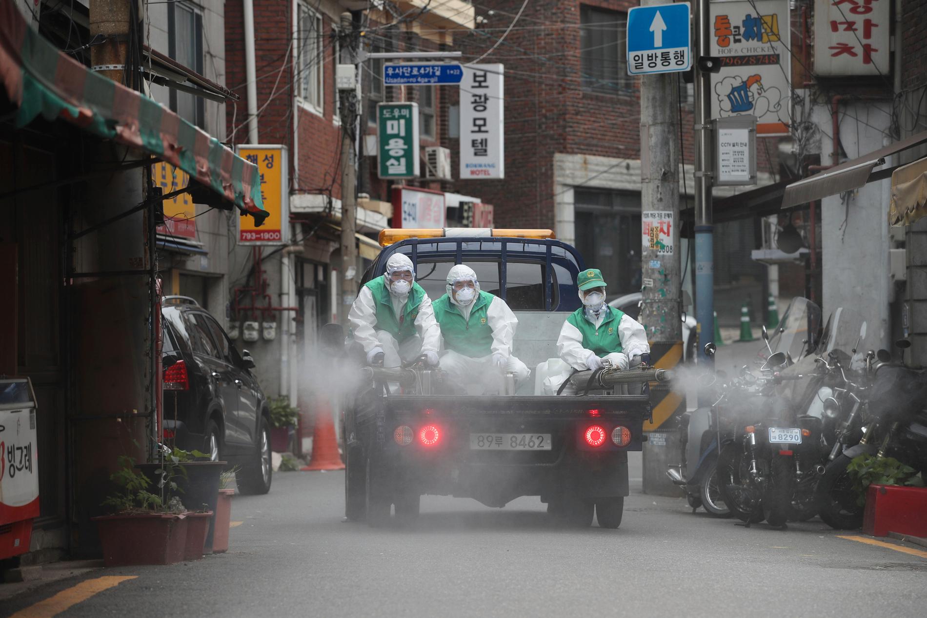 Personer i skyddsmundering sprejar desinficeringsmedel på en gata i Seoul i Sydkorea tidigare i veckan. Metoden får tummen ner av WHO.