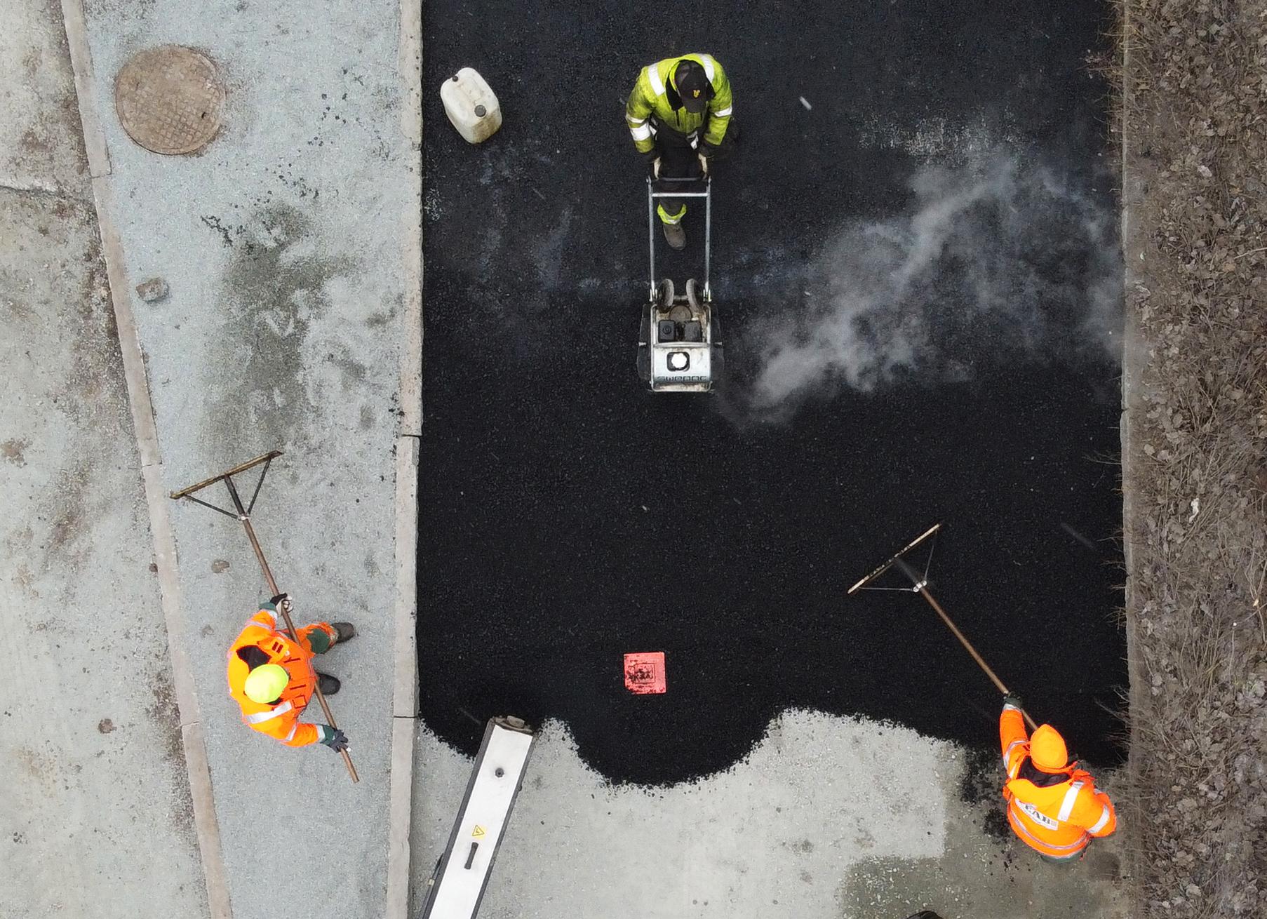 Vägarbetare lägger asfalt på en gata under ett gatuarbete i Enköping. Arkivbild.