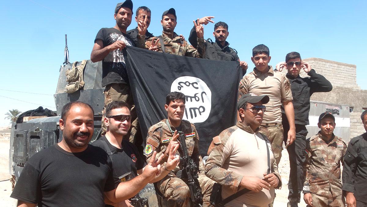 Irakiska säkerhetsstyrkor poserar med en IS-flagga.