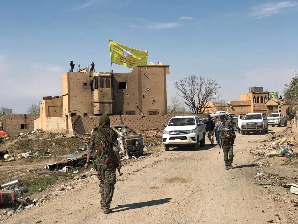 En SDF (Syrian Democratic Forces) flagga vajar i vinden på en byggnad i Baghouz i Syrien.