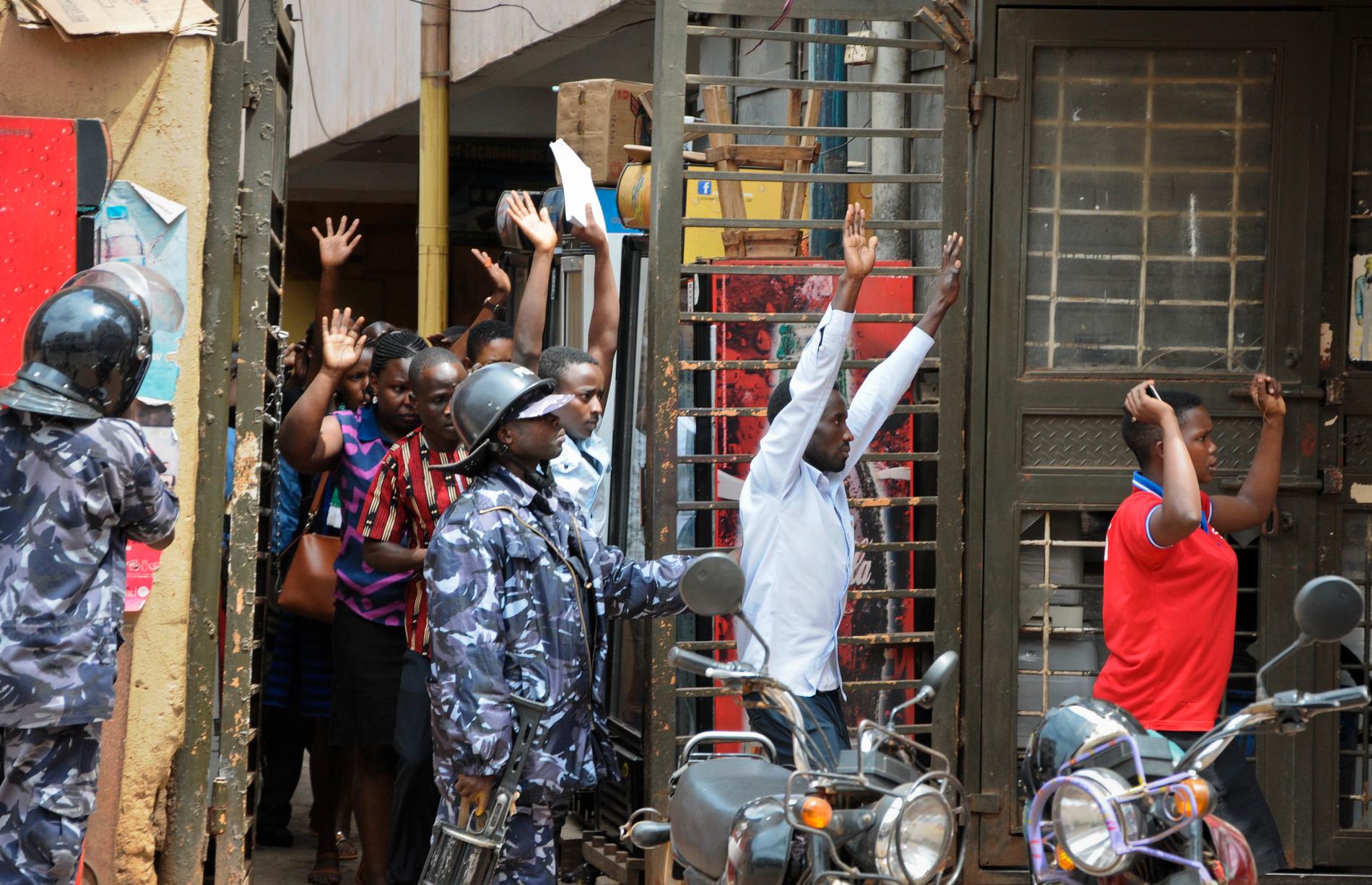 Boende beordras lämna en byggnad i Kampala i samband med att polis försöker skingra de demonstrerande folkmassorna.