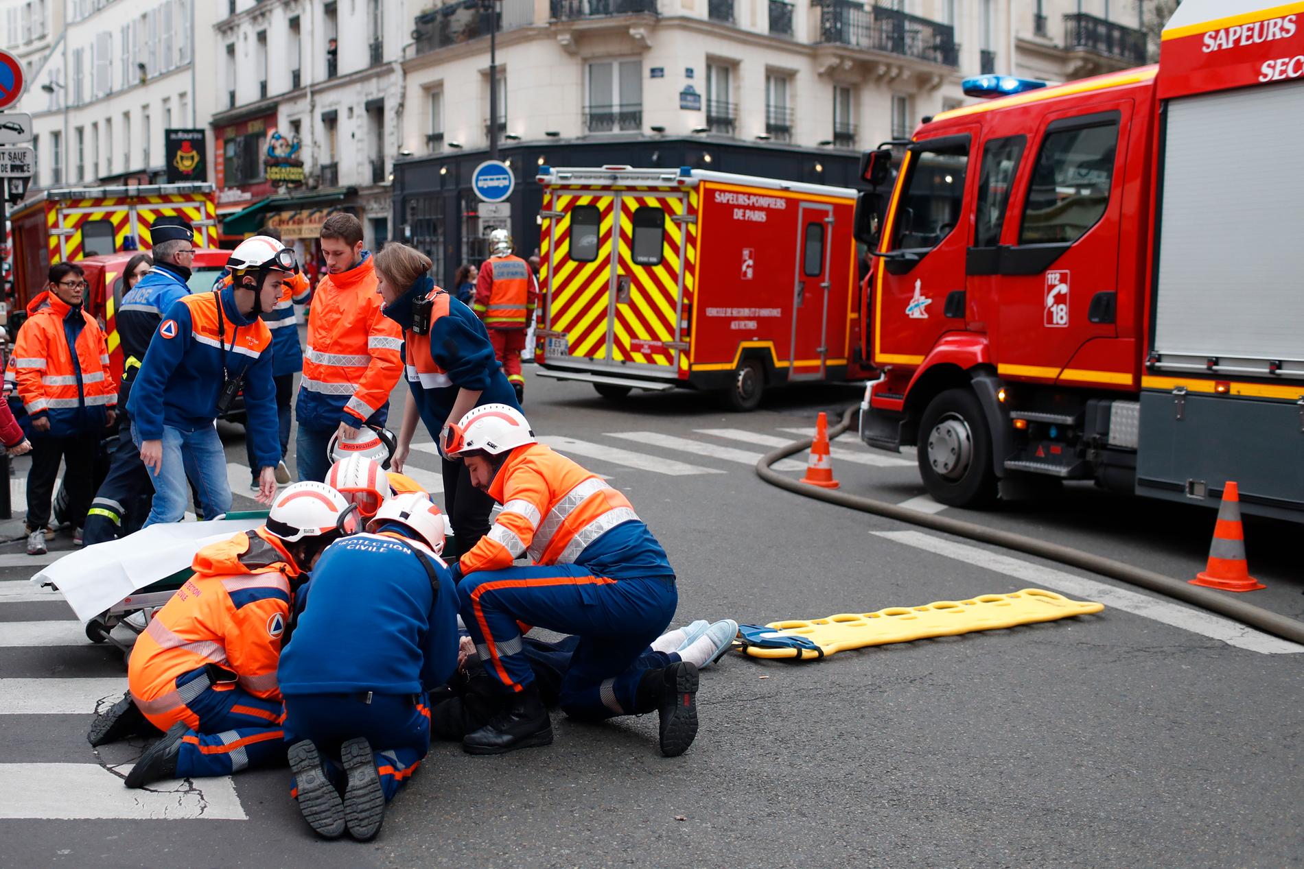Brandmän ger vårt åt en skadad i närheten av den byggnad i centrala Paris där en trolig gasläcka orsakade en kraftig explosion på lördagen.