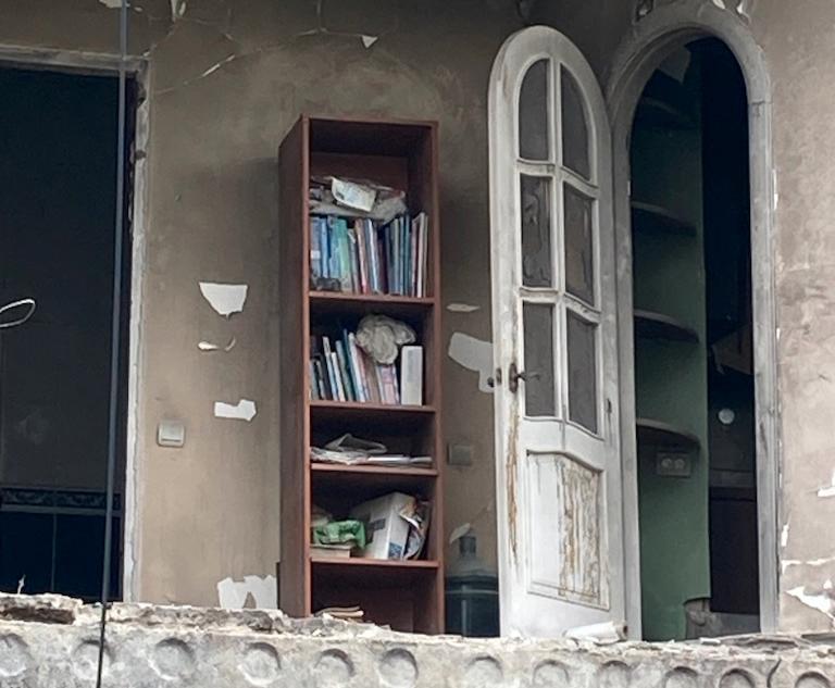 Innanför den bortsprängda väggen syns en bokhylla i Butja, Ukraina. 