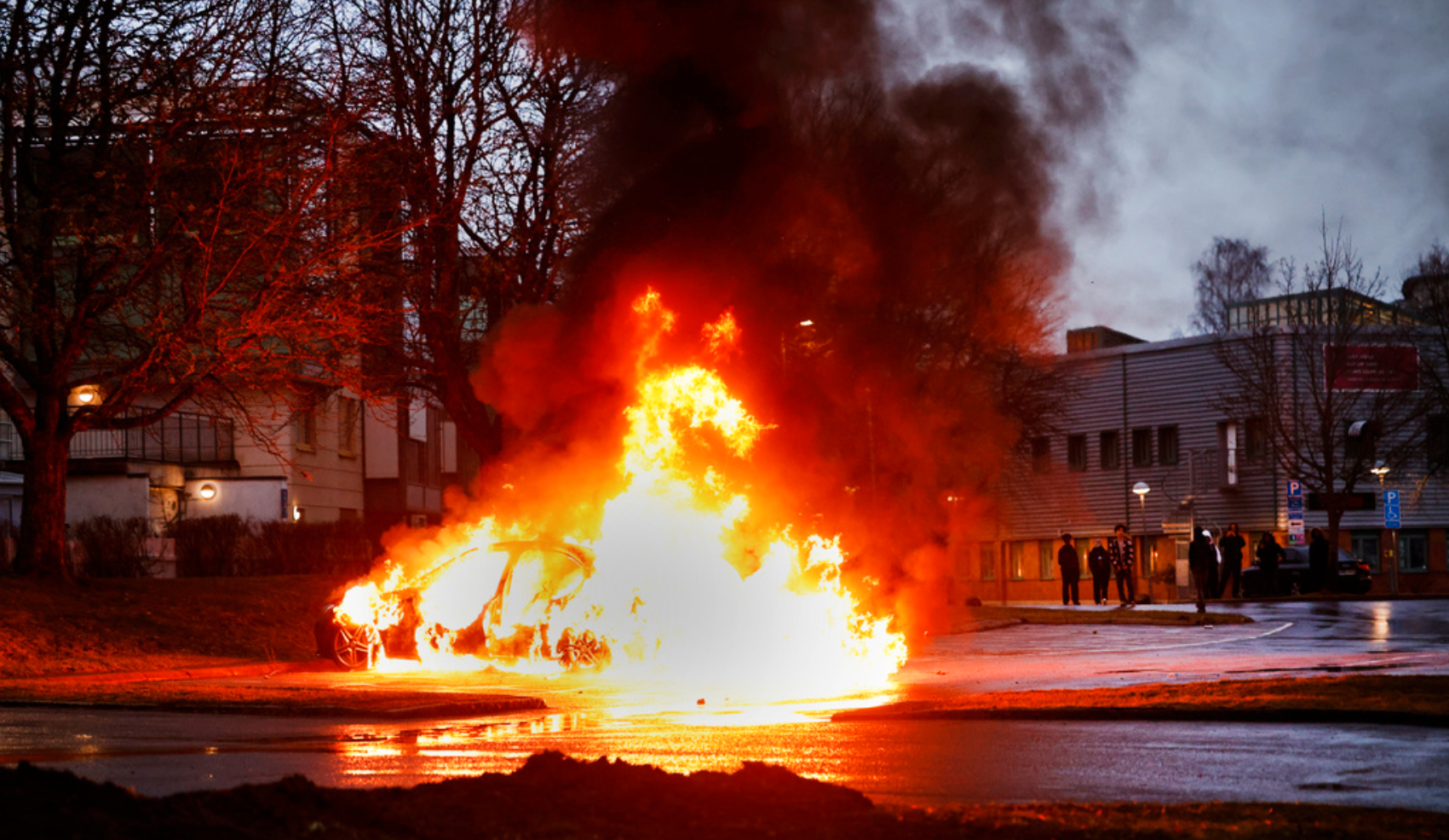 En bil i lågor på en parkering i samband med torsdagens upplopp i Navestad i Norrköping.