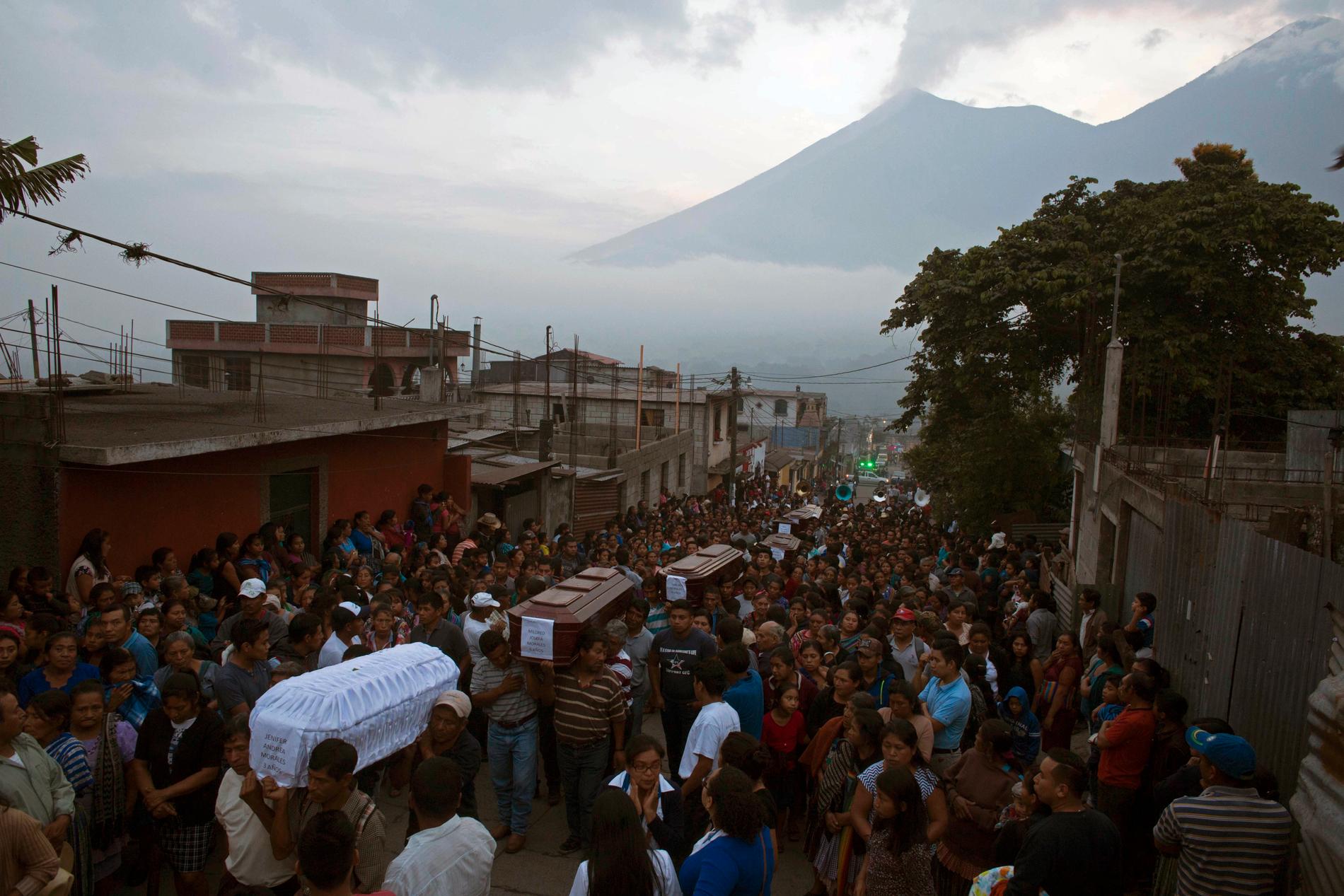 Invånare i byn San Juan Alotenango bär de döda till kyrkogården efter att Volcán de Fuego, som syns i bakgrunden, fått sitt utbrott.