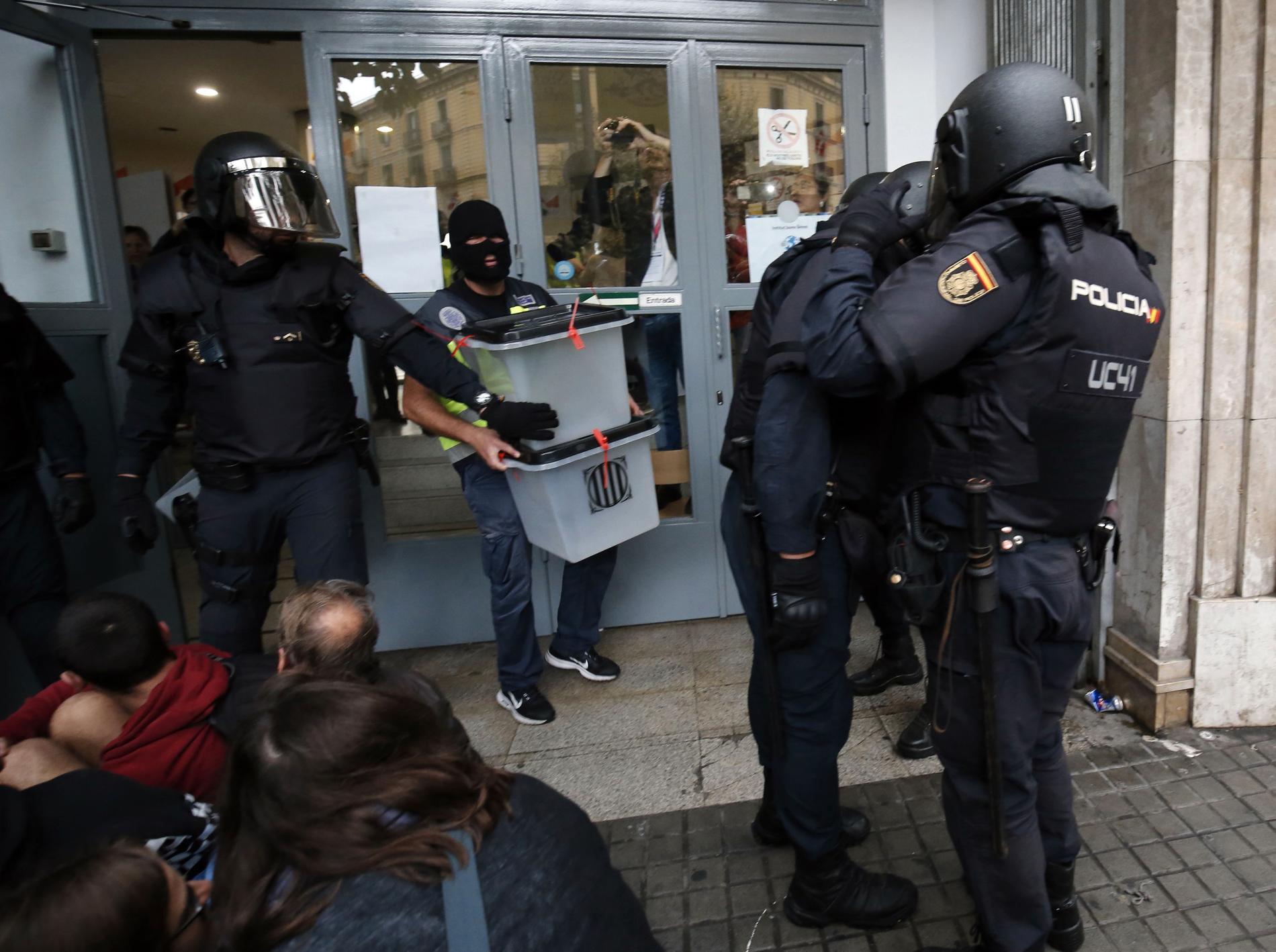 Spansk polis tar hand om valurnor i en vallokal i Barcelona.