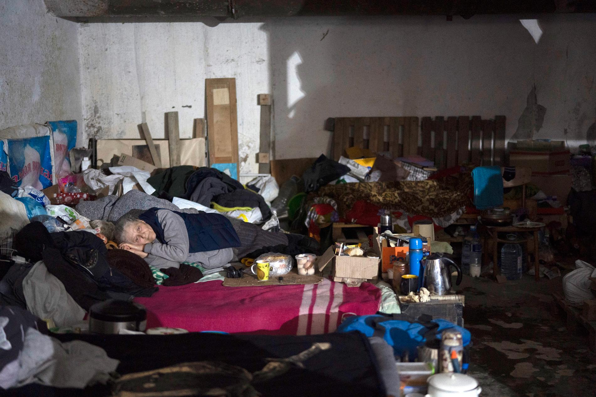 En kvinna vilar på en en madrass i en källare omvandlad till skyddsrum i Severodonetsk. Utanför faller de ryska bomberna. 