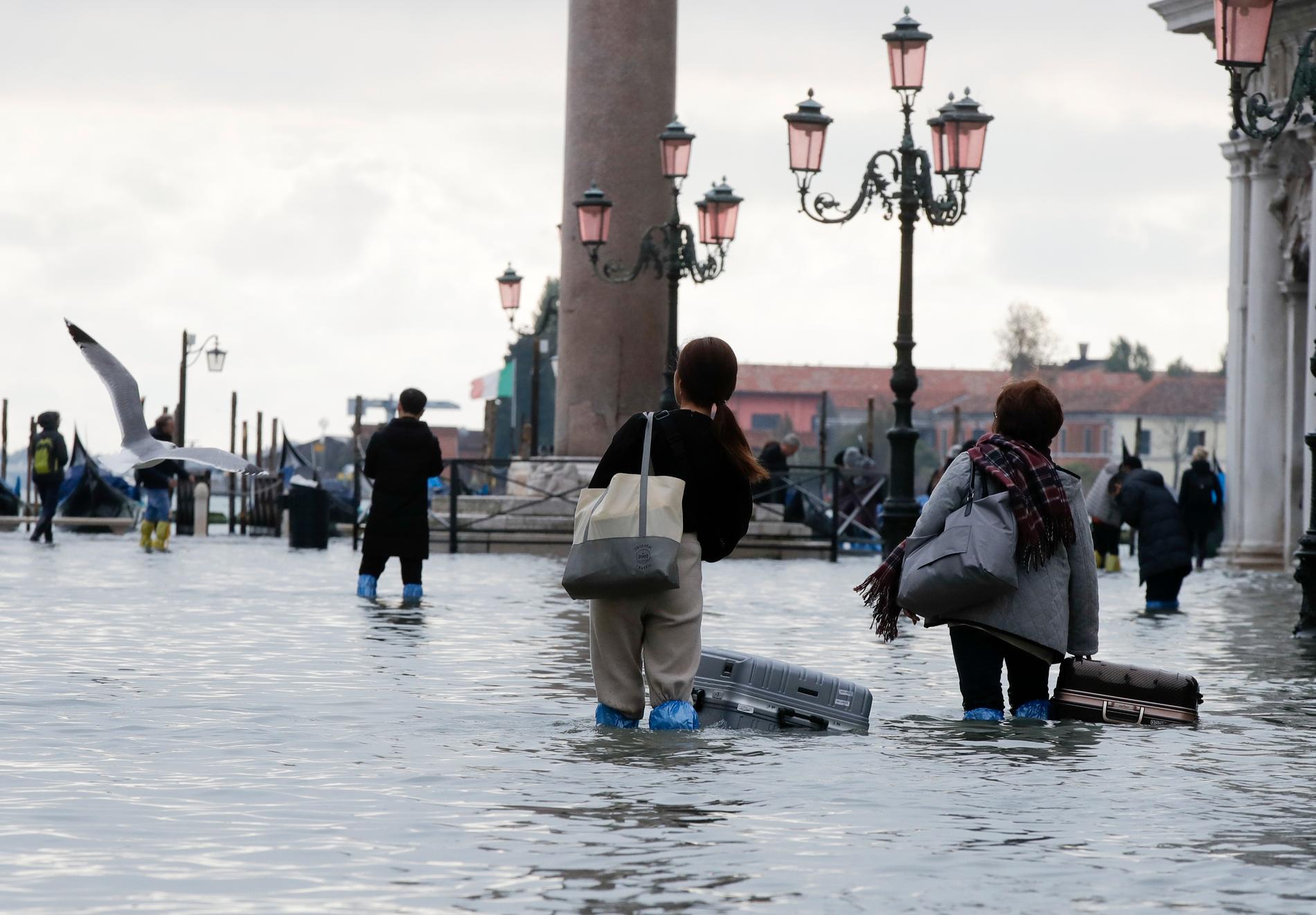 Turister vadar fram med sina väskor på Markusplatsen i Venedig den 13 november förra året.