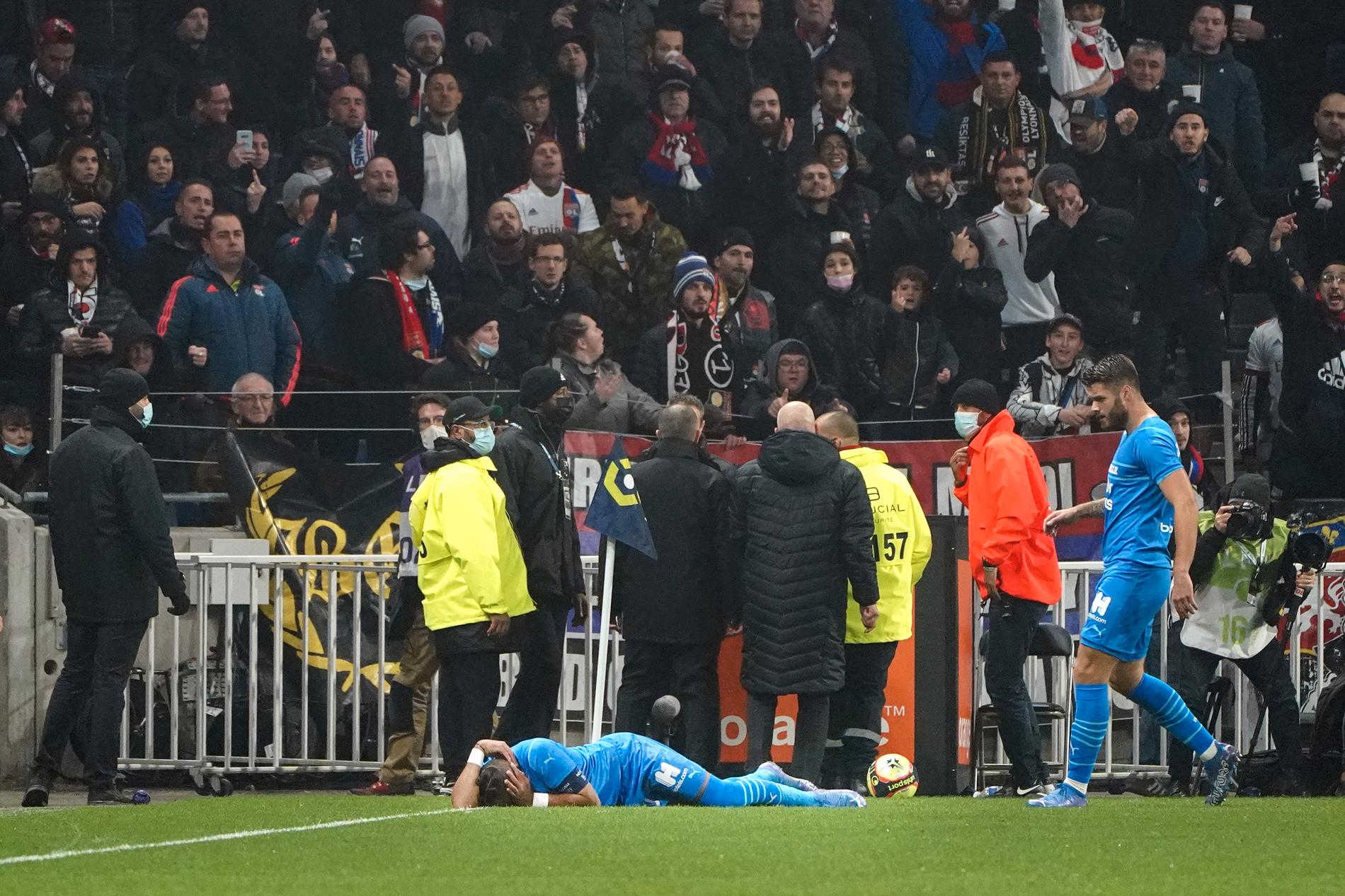 Marseilles Dimitri Payet blir liggande på planen efter att ha fått en flaska kastad i huvudet i bortamatchen mot Lyon. Matchen sköts upp efter skandalen och den franska idrottsministern kallar händelsen för oacceptabel.