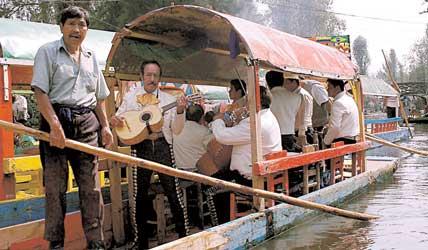 Gondoljären styr fram i sakta mak och mariachimusikerna underhåller familjerna på båtarna i Xochimilco. Foto: LOTTA ZACHRISSON