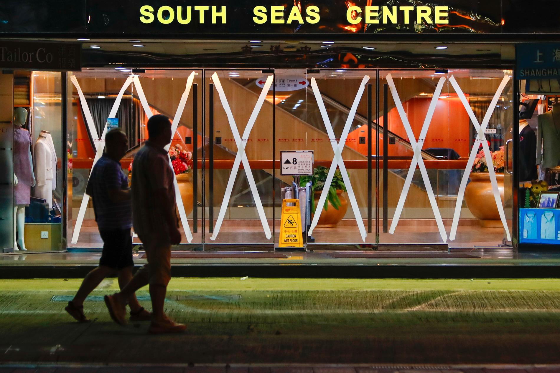 Invånare i Hongkong vid ett köpcentrum som har tejpat sina glasdörrar som en försiktighetsåtgärd när supertyfonen Saola närmar sig.