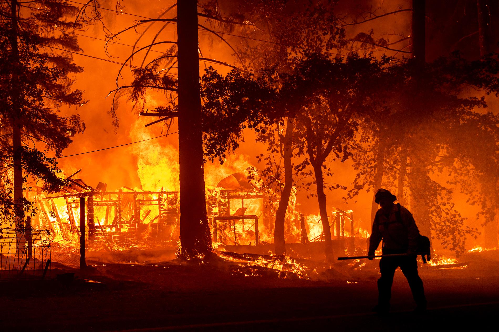 En brandman passerar ett brinnande hem i Plumas County, Kalifornien, den 24 juli.