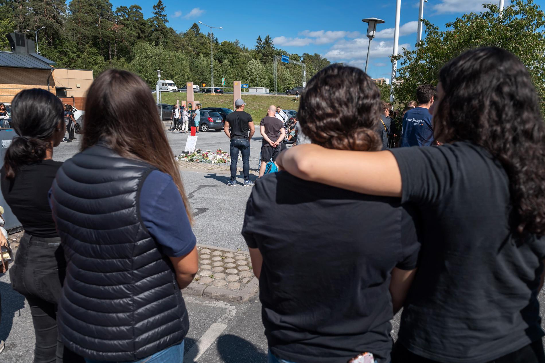 Folk samlas vid blommorna och ljusen på platsen där en tolvårig flicka sköts ihjäl vid en bensinmack i Hallunda i Botkyrka, söder om Stockholm natten mot söndagen.