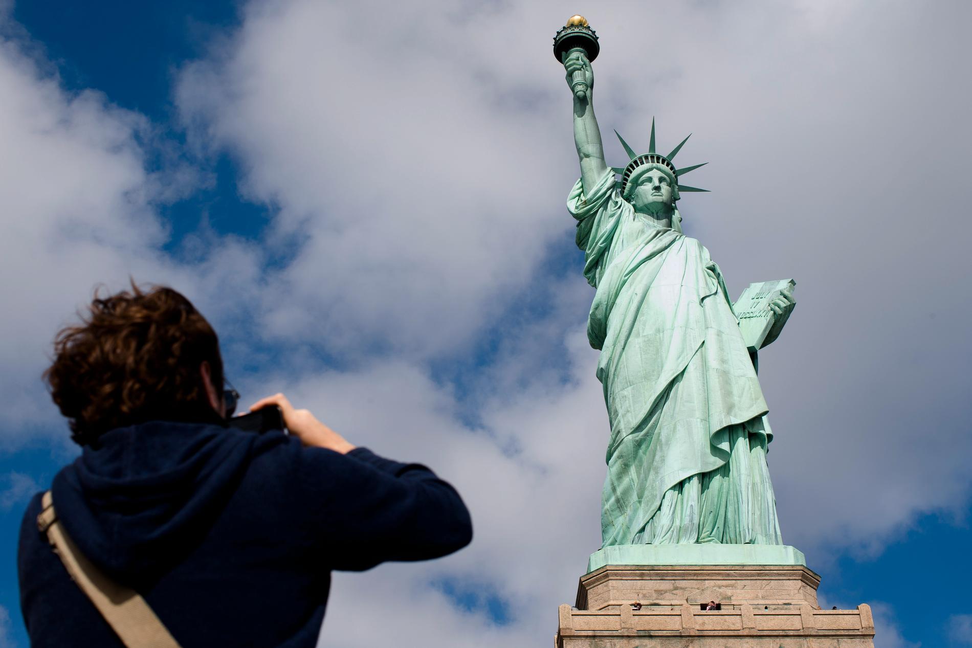 En av de 62,5 miljoner turisterna i New York förra året tar en bild av frihetsgudinnan.