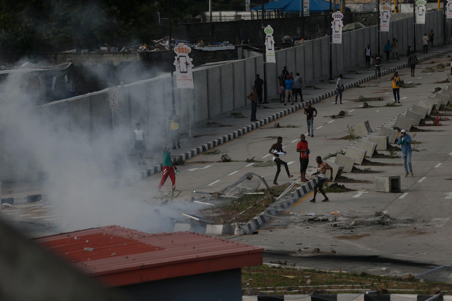 Demonstranter tar till flykten då polis sätter in tårgas för att skingra protester i Lagos på onsdagen.