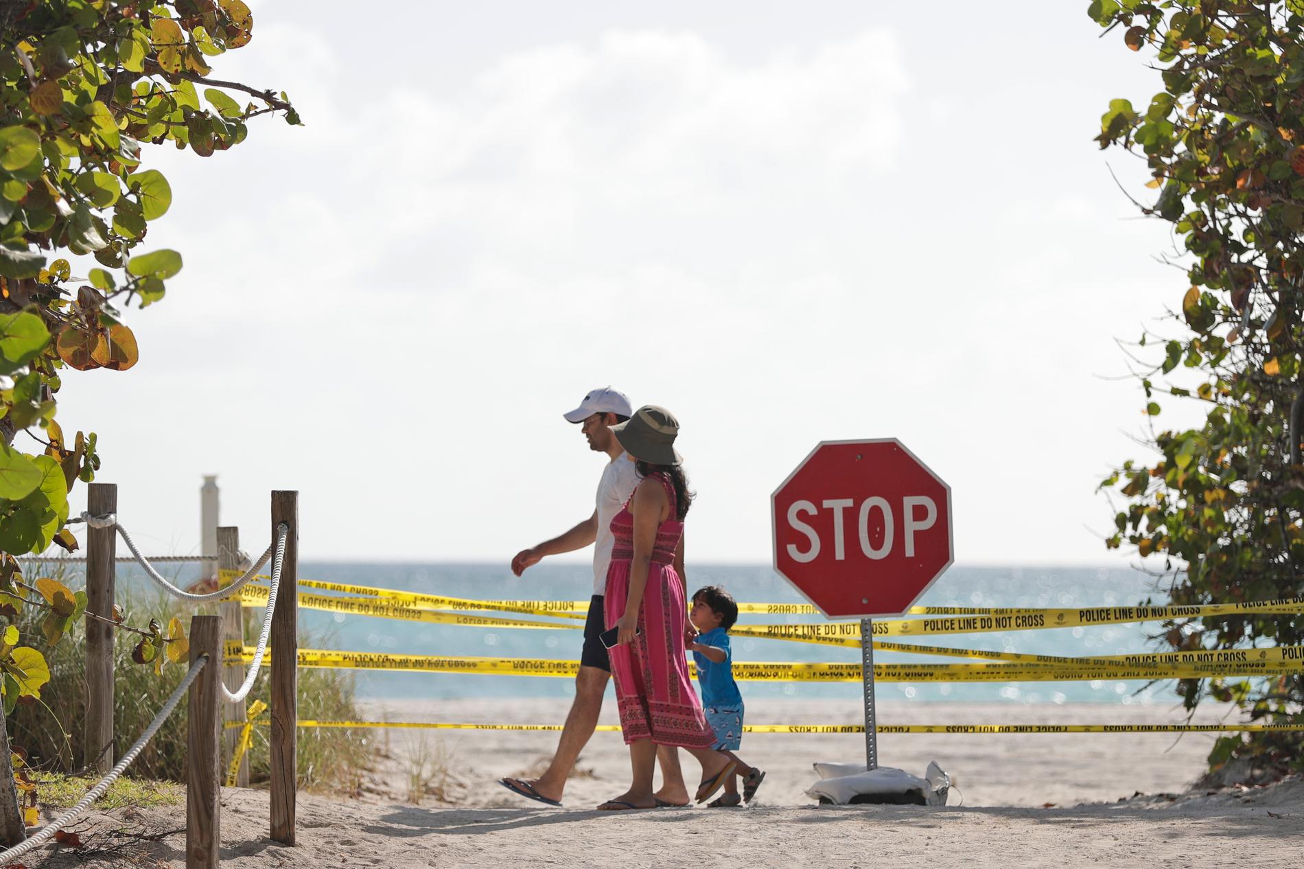SURFSIDE, USA En familj passerar en avspärrad strand i Surfside, Florida, på lördagen.