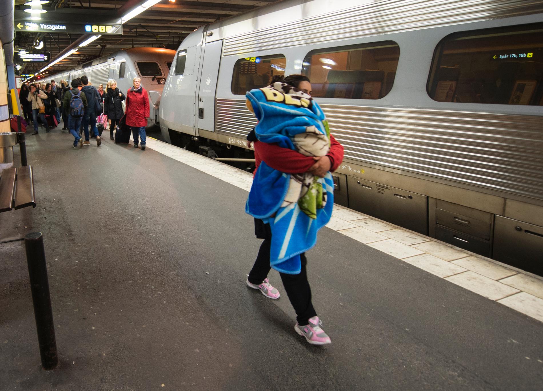 En kvinna med ett sovande barn anländer till Stockholm med tåget från Malmö/Köpenhamn under hösten 2015, då många flyktingar kom till Sverige. Arkivbild.