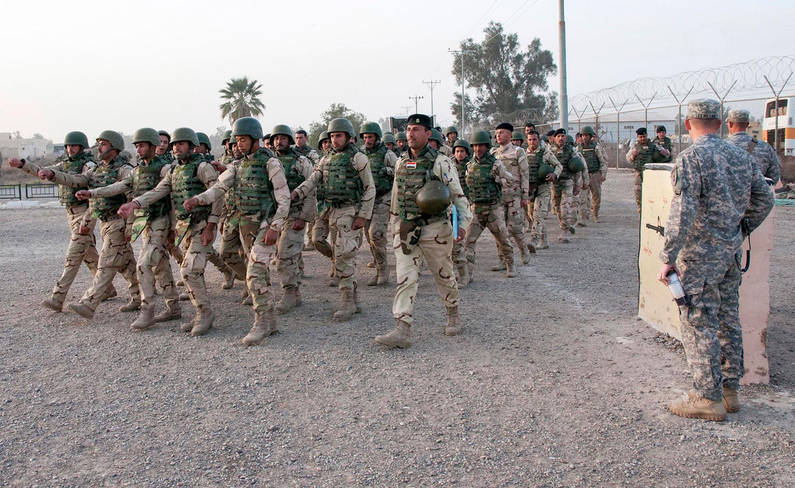 Irakiska soldater marscherar förbi amerikanska officerare.