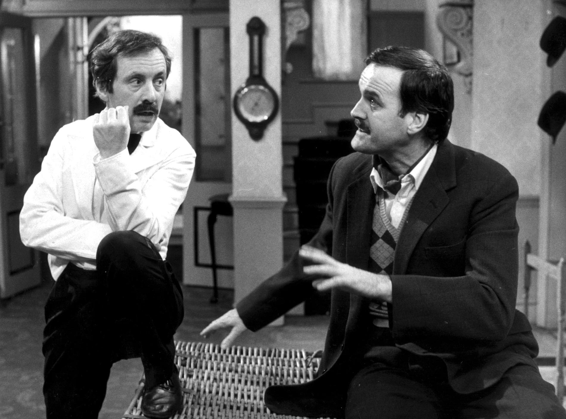 Andrew Sachs som Manuel och John Cleese som Basil Fawlty i komediserien "Pang i Bygget".