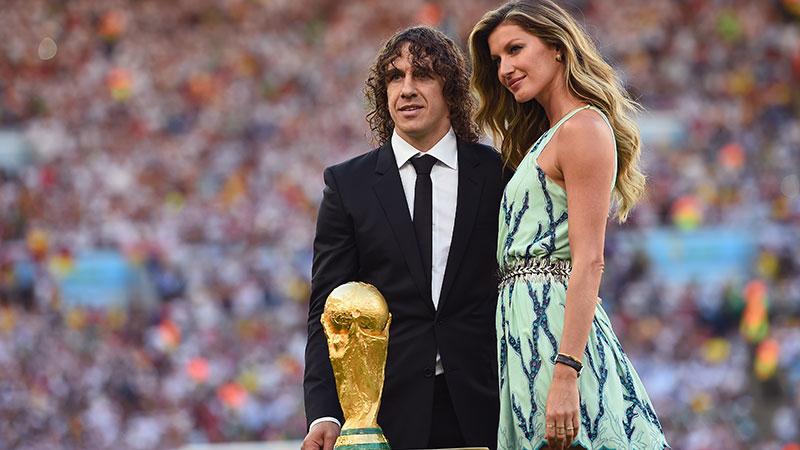 Regerande världsmästaren Carles Puyol och modellen Gisele Bundchen poserar med VM-pokalen.