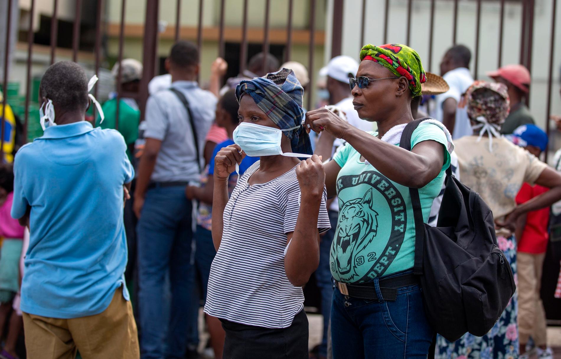 En kvinna får hjälp med sitt munskydd i Pétionville nära Haitis huvudstad Port-au-Prince.